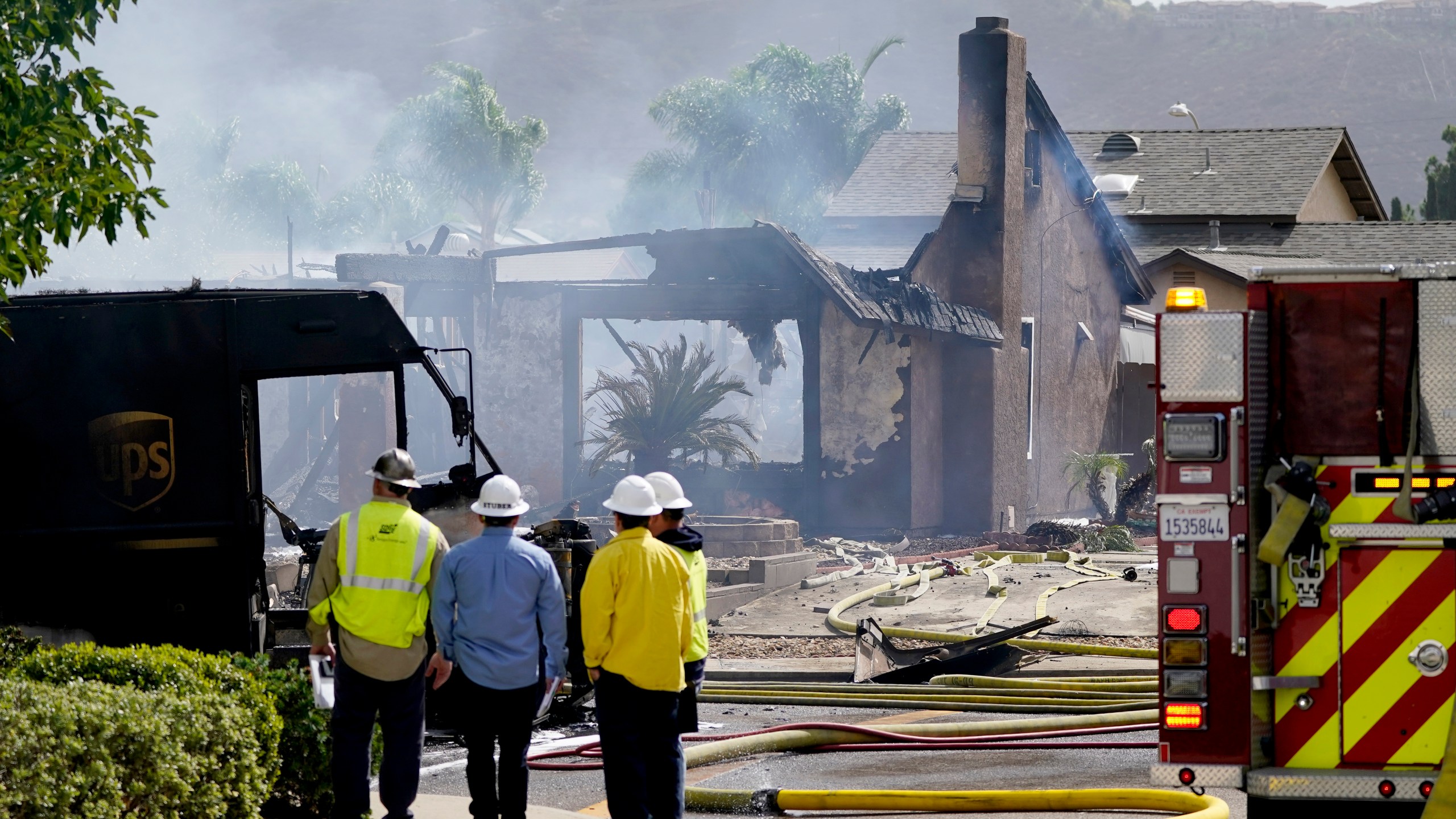 Fire and safety crews work the scene of a plane crash, Monday, Oct. 11, 2021, in Santee, Calif. At least two people were killed and two others were injured when the small plane crashed into a suburban Southern California neighborhood, setting two homes ablaze, authorities said. (AP Photo/Gregory Bull)