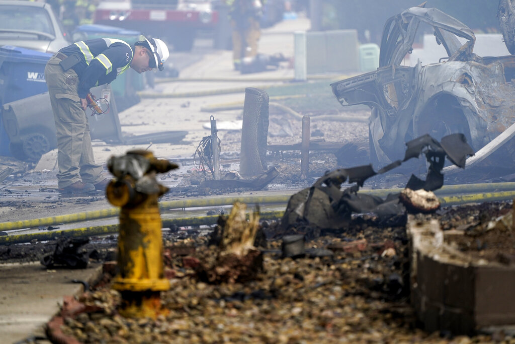 A fire official looks over the scene of a small plane crash, Monday, Oct. 11, 2021, in Santee, Calif. (AP Photo/Gregory Bull)