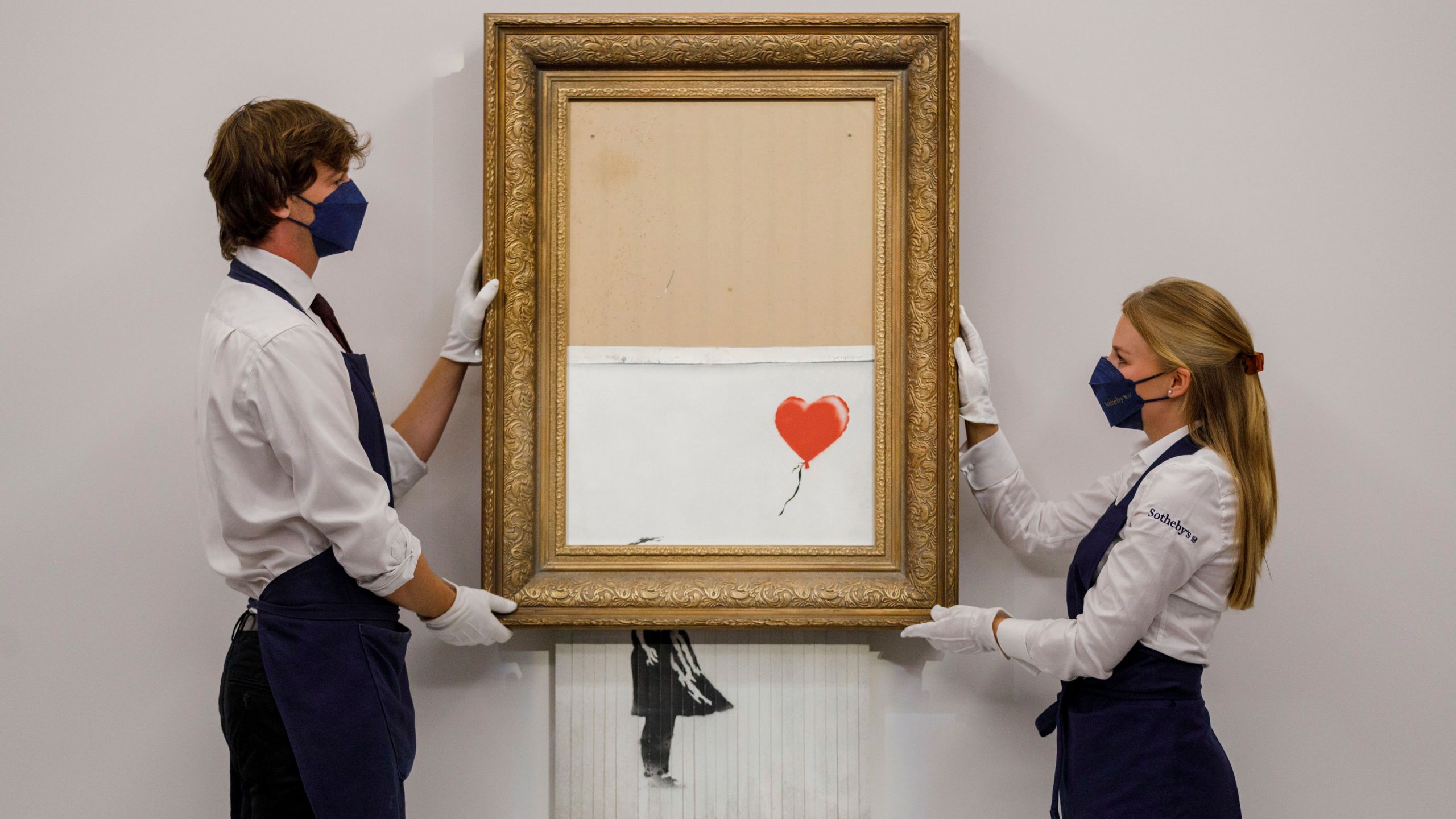 In this handout photo provided by Sotheby's Auction House, the auction for Banksy's "Love is the Bin" takes place in London, Thursday, Oct. 14, 2021. A work by British street artist Banksy that sensationally self-shredded just after it sold for $1.4 million has sold again for $25.4 million at an auction on Thursday. “Love is in the Bin” was offered by Sotheby’s in London, with a presale estimate of $5.5 million to $8.2 million. (Sotheby's Auction House via AP)