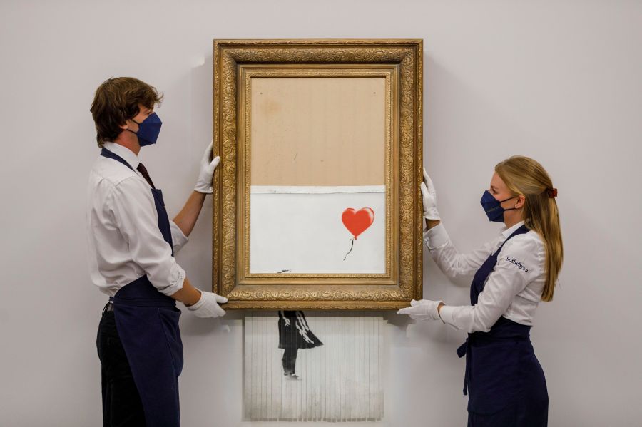 In this handout photo provided by Sotheby's Auction House, the auction for Banksy's "Love is the Bin" takes place in London, Thursday, Oct. 14, 2021. A work by British street artist Banksy that sensationally self-shredded just after it sold for $1.4 million has sold again for $25.4 million at an auction on Thursday. “Love is in the Bin” was offered by Sotheby’s in London, with a presale estimate of $5.5 million to $8.2 million. (Sotheby's Auction House via AP)