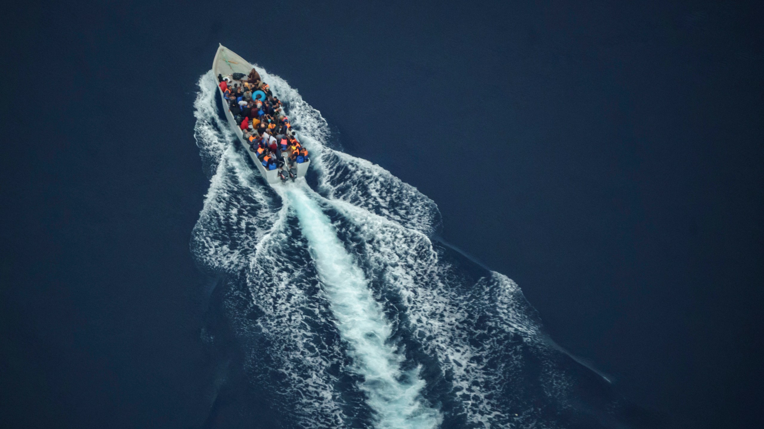 Migrants navigate on an overcrowded wooden boat in the Central Mediterranean Sea between North Africa and the Italian island of Lampedusa, Saturday, Oct. 2, 2021, as seen from aboard the humanitarian aircraft Seabird. At least 23,000 people have died or disappeared trying to reach Europe since 2014, according to the United Nations' migration agency. Despite the risks, many migrants say they'd rather die trying to reach Europe than be returned to Libya. (AP Photo/Renata Brito)