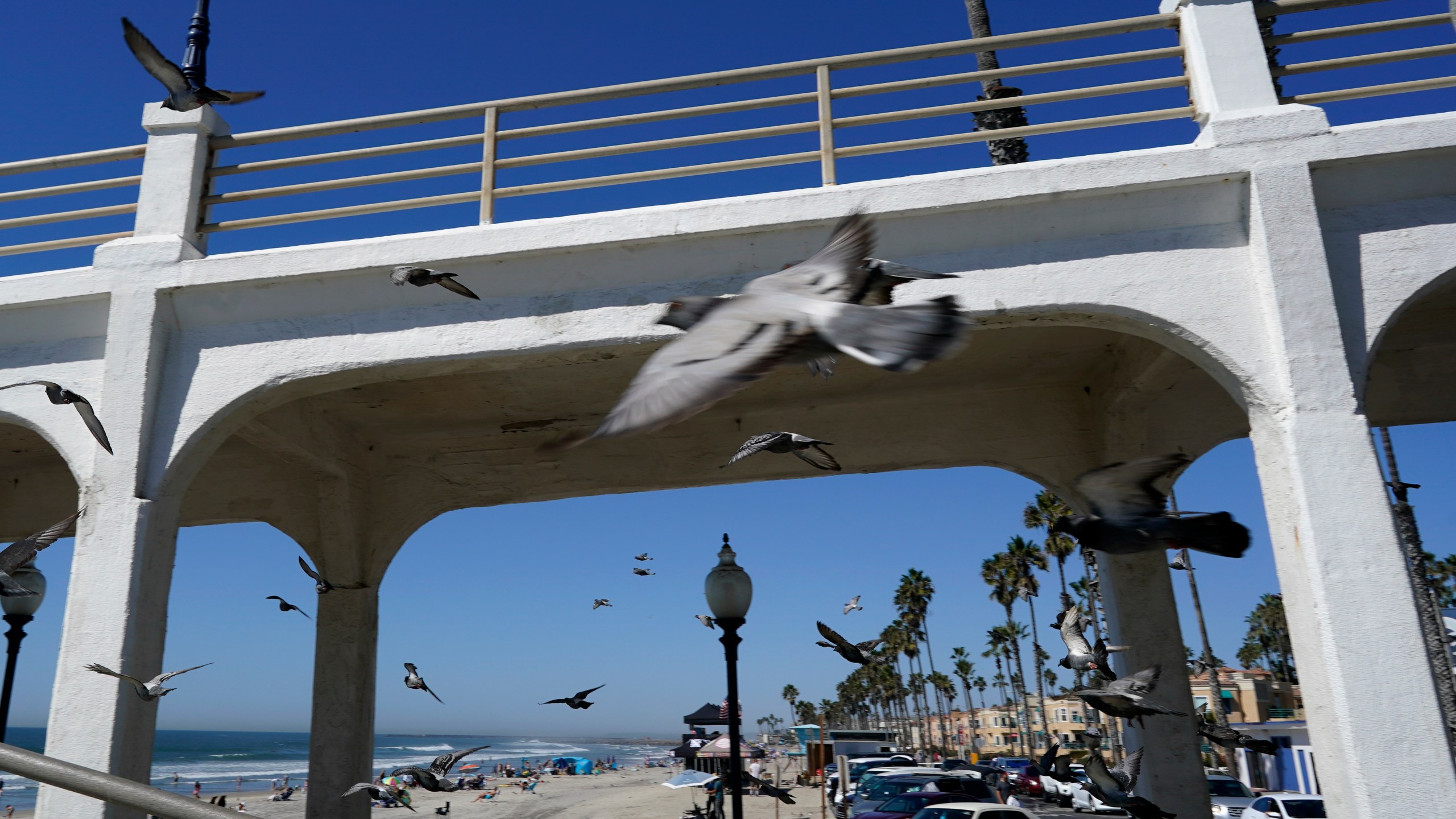 Birds fly past a bridge connecting the Oceanside pier to Pacific Street Friday, Oct. 15, 2021, in Oceanside, Calif. (AP Photo/Gregory Bull)