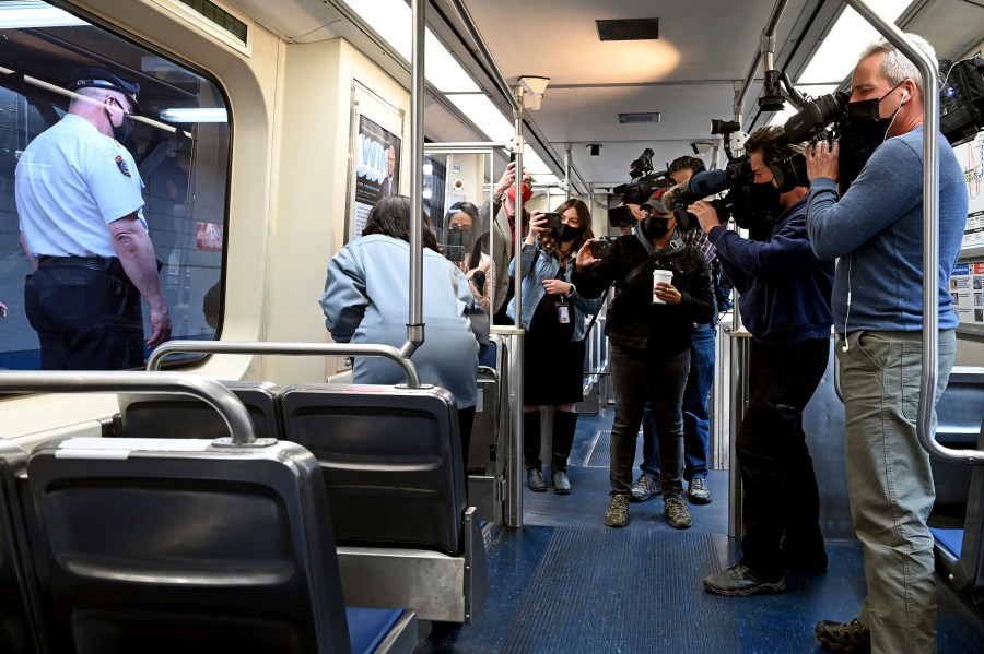 SEPTA Transit Police Chief Thomas Nestel III, seen through window at left, stands by following a news conference on an El platform at the 69th Street Transportation Center, Monday, Oct. 18, 2021, in Philadelphia, following a brutal rape on the El over the weekend. SEPTA subway elevated Chief Officer Chrystalle Hooper, center, demonstrates the emergency call boxes on SEPTA trains and how to properly contact police from their cars. (Tom Gralish/The Philadelphia Inquirer via AP)