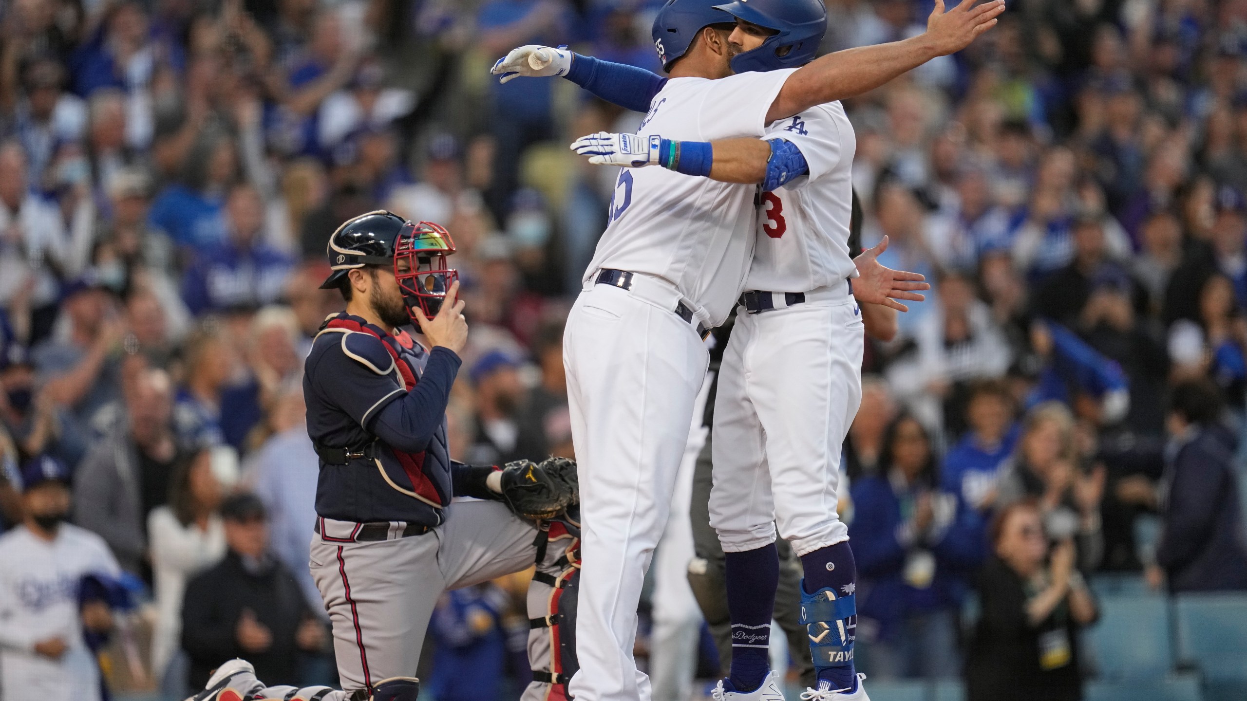 Los Angeles Dodgers' Albert Pujols hugs Chris Taylor after Taylor's two-run home run in the second inning against the Atlanta Braves in Game 5 of baseball's National League Championship Series Thursday, Oct. 21, 2021, in Los Angeles. Pujols scored on the hit. (AP Photo/Ashley Landis)