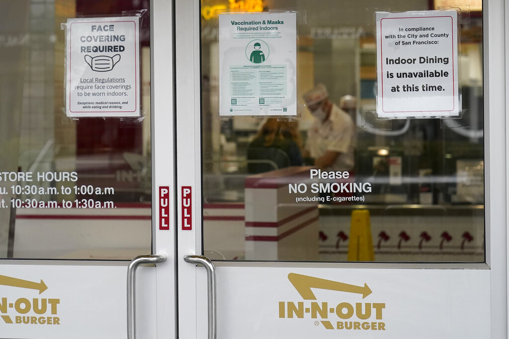 In this Oct. 20, 2021, file photo, signs advising vaccination and face mask requirements and no indoor dining are displayed on the door of an In-N-Out restaurant in San Francisco's Fisherman's Wharf. The restaurant's indoor dining was shut down this month by health authorities for not demanding proof of vaccination. (AP Photo/Jeff Chiu, File)