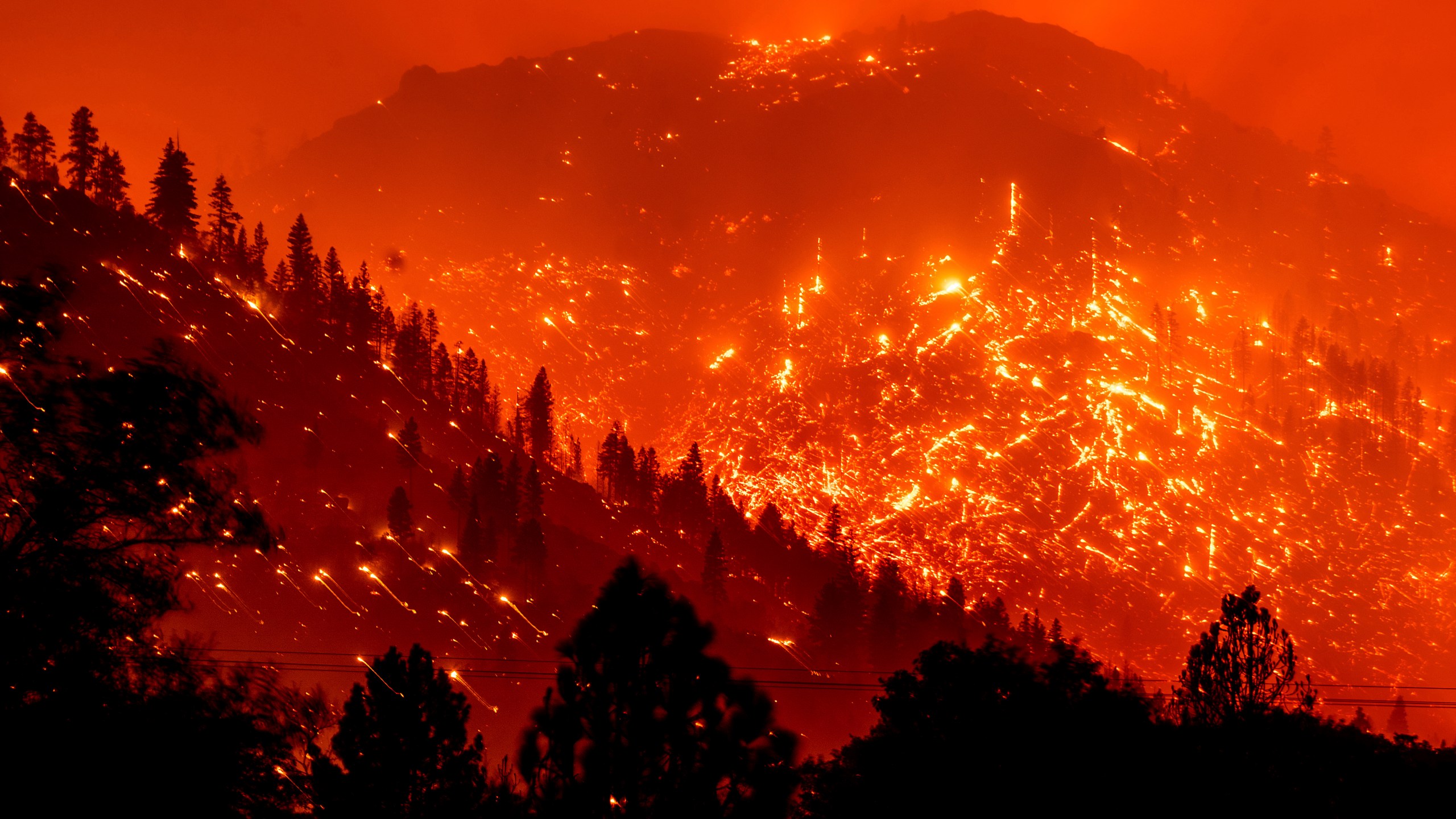 In this Aug. 17, 2021, file photo, embers light up hillsides as the Dixie Fire burns near Milford in Lassen County, Calif. (AP Photo/Noah Berger, File)