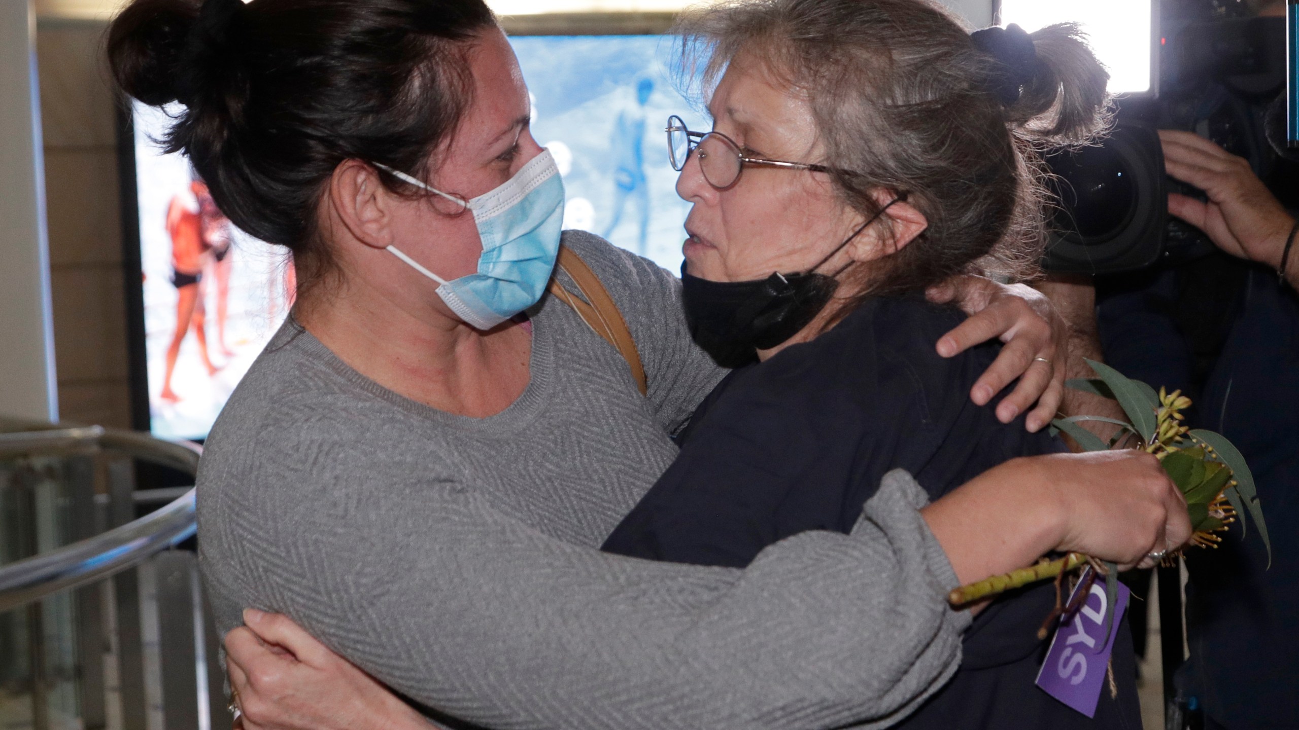 A woman, right, is embraced by. a loved one after arriving on a flight from Los Angeles at Sydney Airport as Australia open its borders for the first time in 19 months in Sydney, Monday, Nov. 1, 2021. International travel will be initially restricted to Sydney's airport because New South Wales has the highest vaccination rate of any state. (AP Photo/Rick Rycroft)