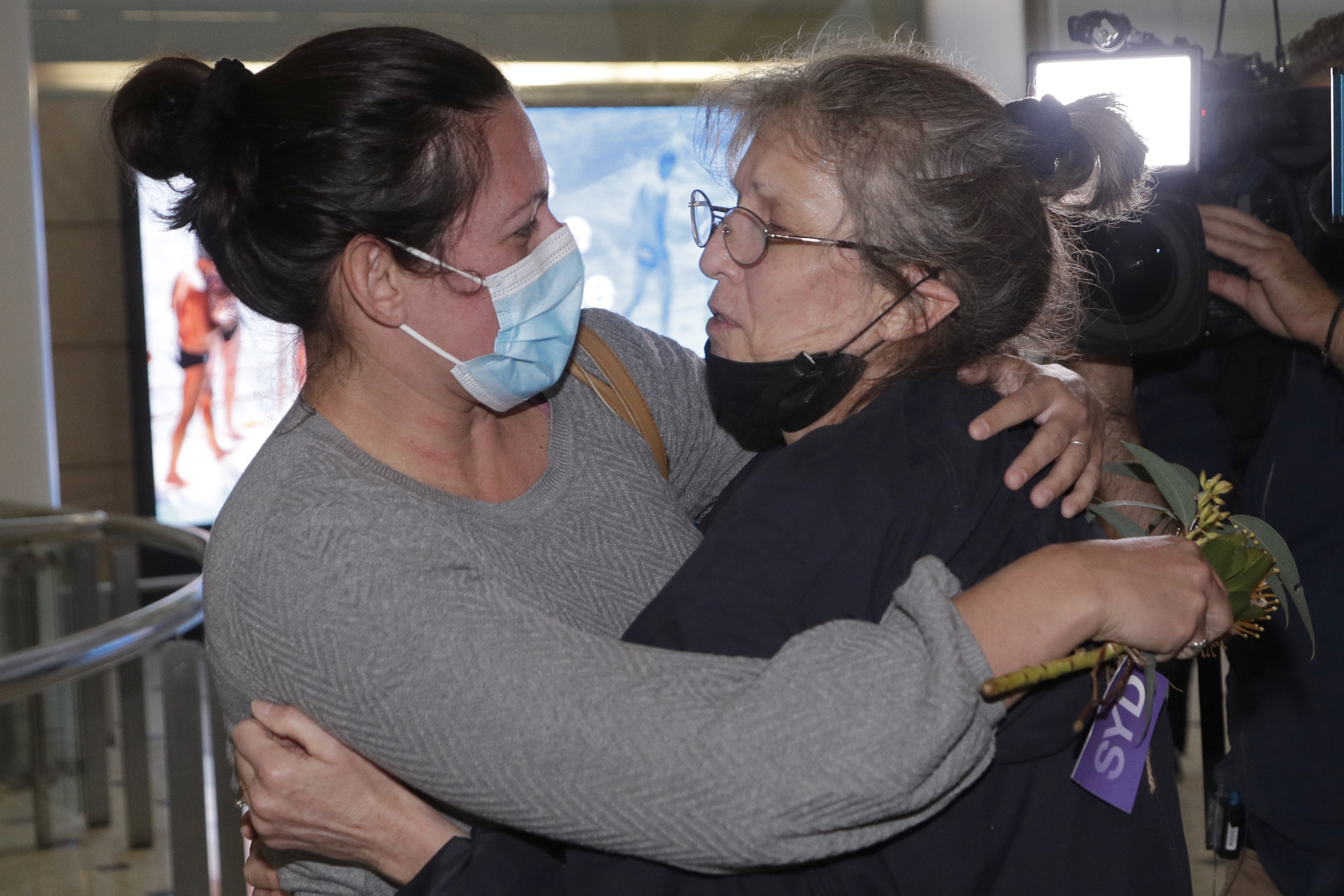 A woman, right, is embraced by. a loved one after arriving on a flight from Los Angeles at Sydney Airport as Australia open its borders for the first time in 19 months in Sydney, Monday, Nov. 1, 2021. International travel will be initially restricted to Sydney's airport because New South Wales has the highest vaccination rate of any state. (AP Photo/Rick Rycroft)