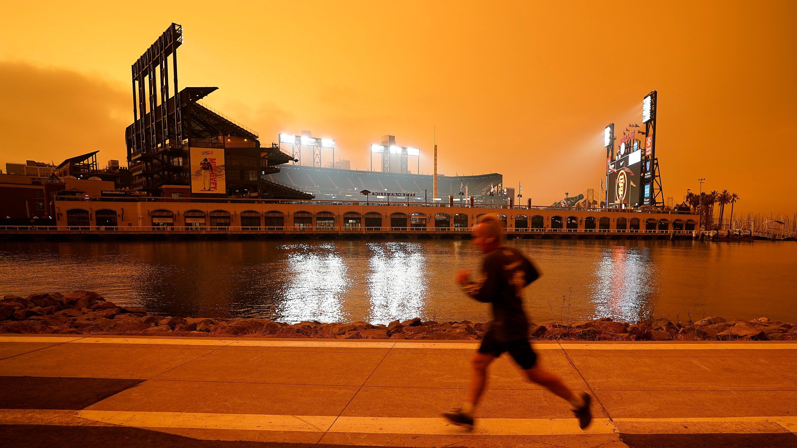 In this Wednesday, Sept. 9, 2020 file photo, a jogger runs along McCovey Cove outside Oracle Park in San Francisco, under darkened skies from wildfire smoke. Health problems tied to climate change are all getting worse, according to two reports published in the medical journal Lancet on Wednesday, Oct. 20, 2021. An unprecedented Pacific Northwest and Canadian heat wave hit this summer, which a previous study showed couldn't have happened without human-caused climate change. (AP Photo/Tony Avelar)