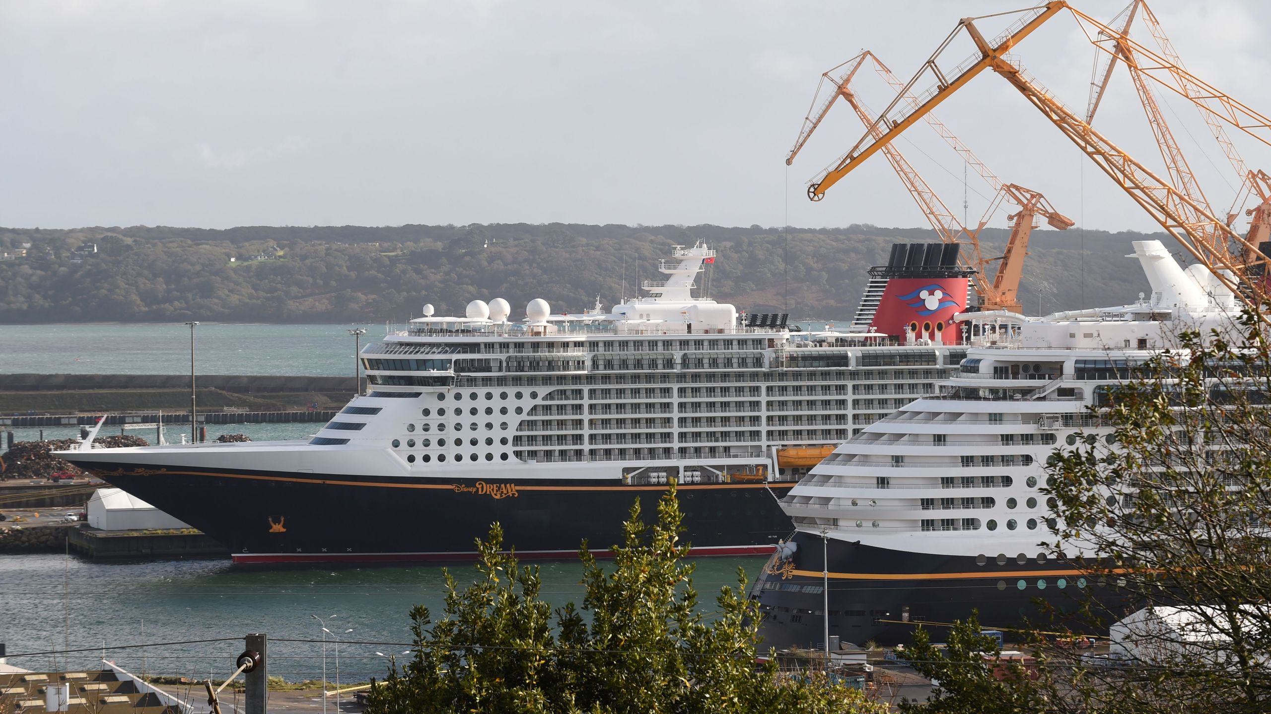 A picture taken on October 26, 2020 shows the Disney Dream liner (L), the third liner of the Disney Cruise Line, and the Disney Fantasy (R), owned by the Walt Disney Company cruise operator in Brest harbour, western France. (JEAN-FRANCOIS MONIER/AFP via Getty Images)