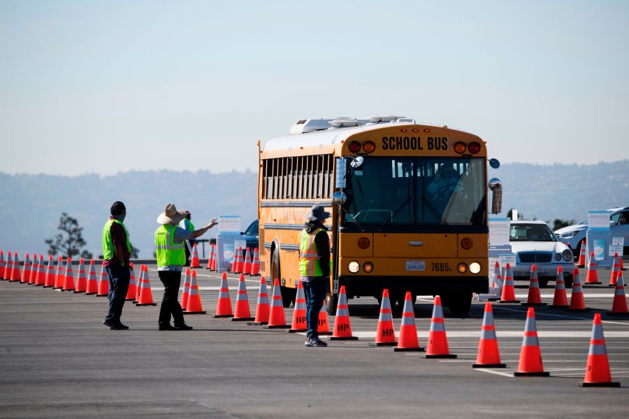 A school bus transporting education workers arrives at a mass vaccination site near SoFi stadium on March 1, 2021 in Inglewood. (PATRICK T. FALLON/AFP via Getty Images)