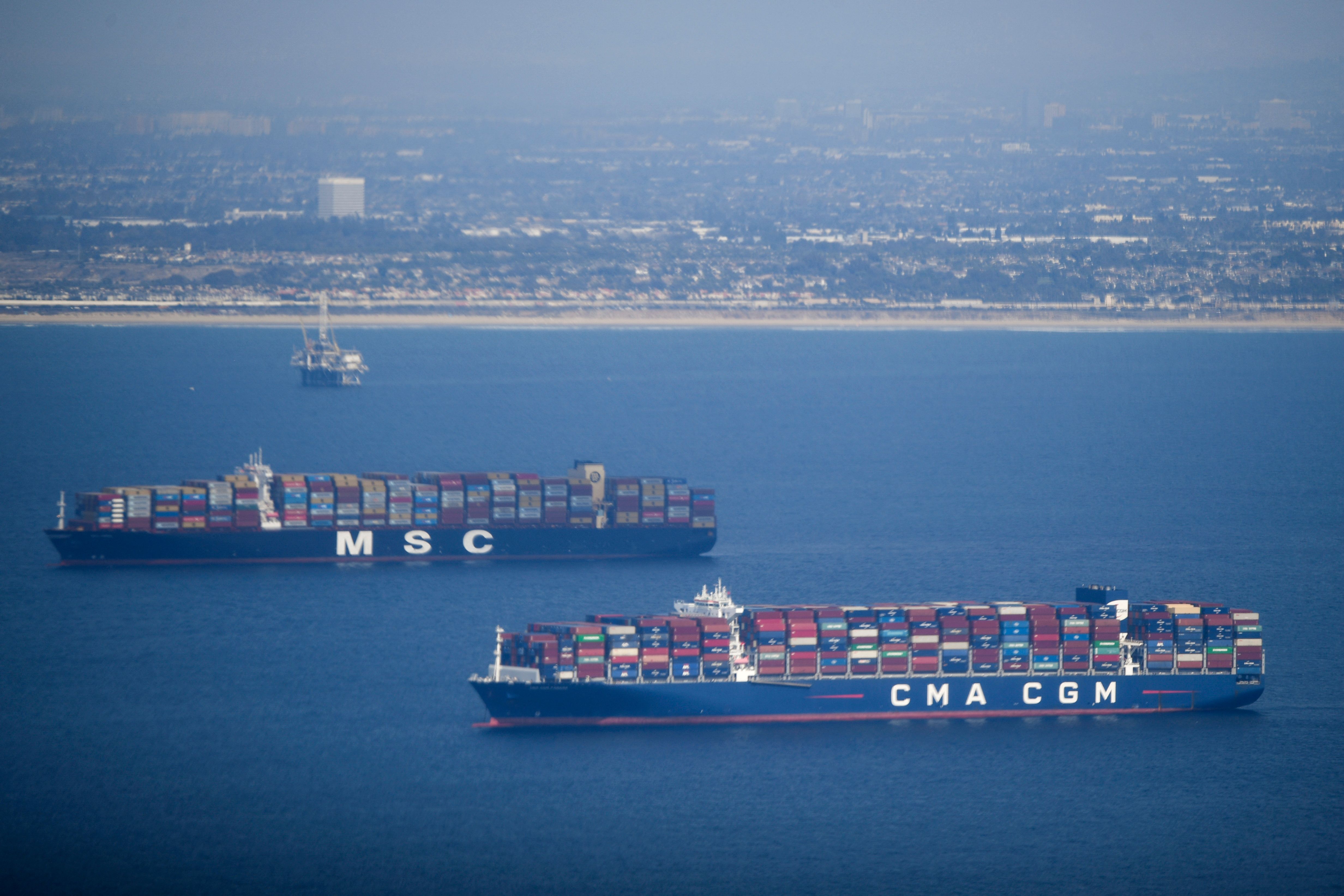 An oil platform and cargo container ships offshore along the coastline are seen from a U.S. Coast Guard HC-27J Spartan aircraft during a media flight on Oct. 6, 2021, after an oil spill in the Pacific Ocean in Orange County. (Patrick T. Fallon / AFP / Getty Images)