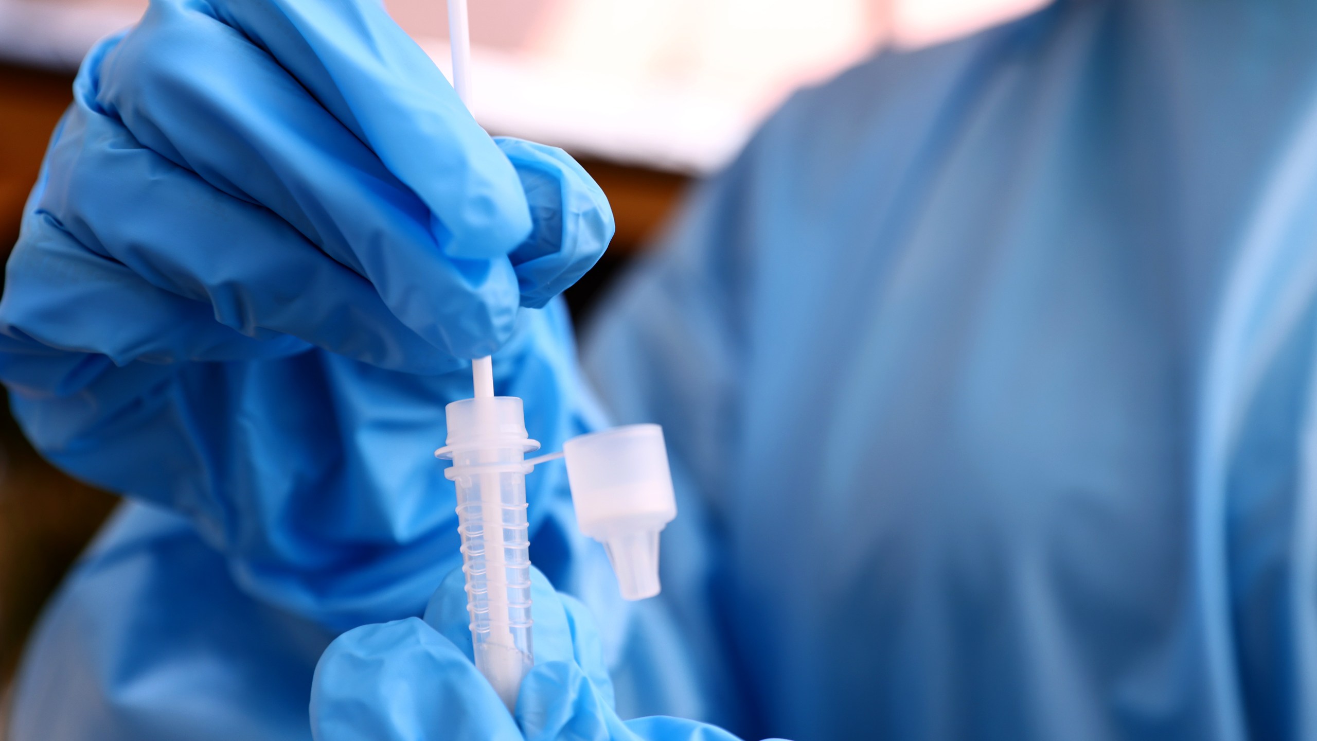 A registered nurse stirs a nasal swab in testing solution after administering a coronavirus on July 14, 2021 in Los Angeles, California. (Mario Tama/Getty Images)