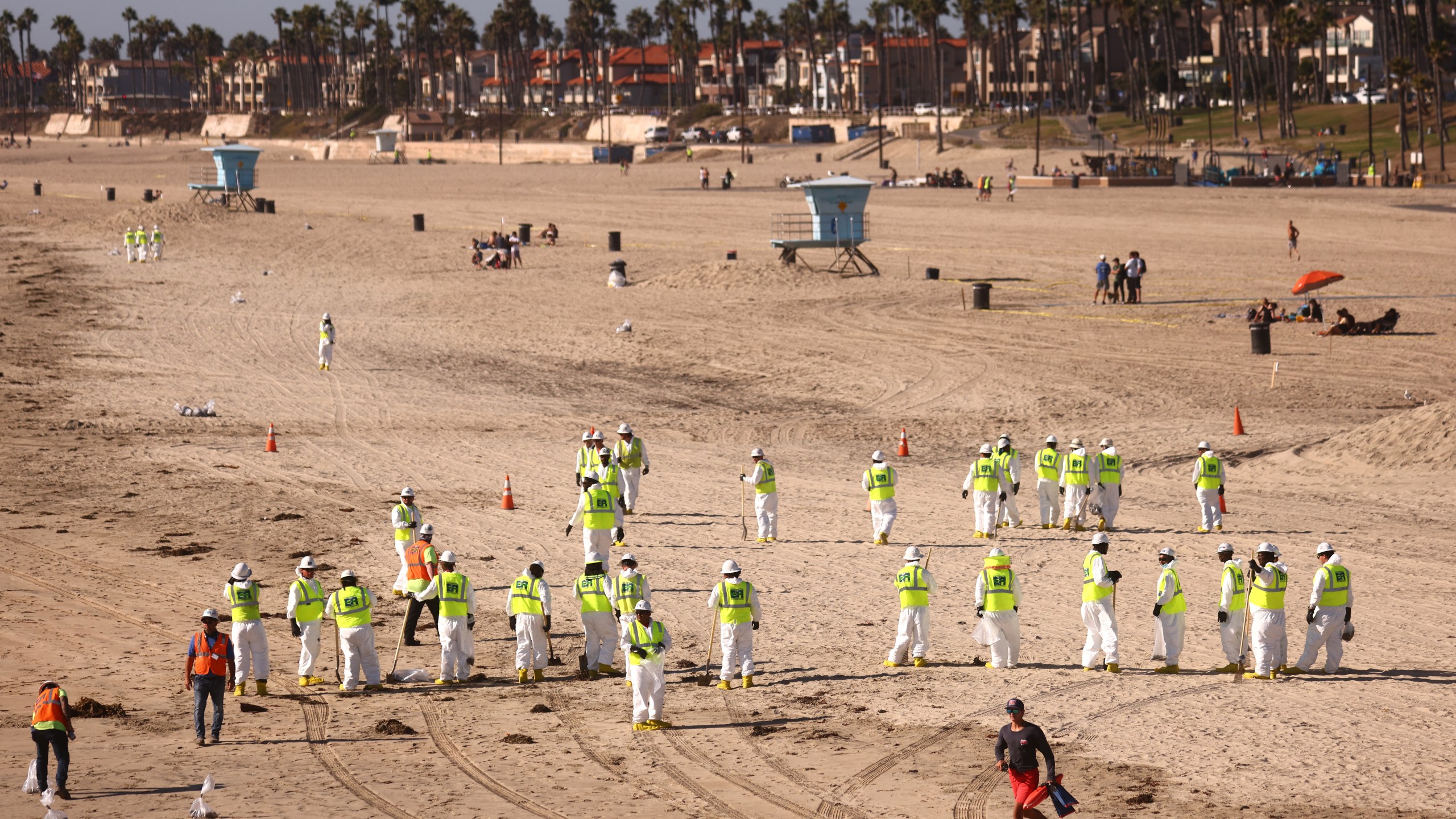 Cleanup workers search for contaminated sand and seaweed on a mostly empty Huntington Beach about one week after an oil spill from an offshore oil platform on Oct. 9, 2021. (Mario Tama/Getty Images)