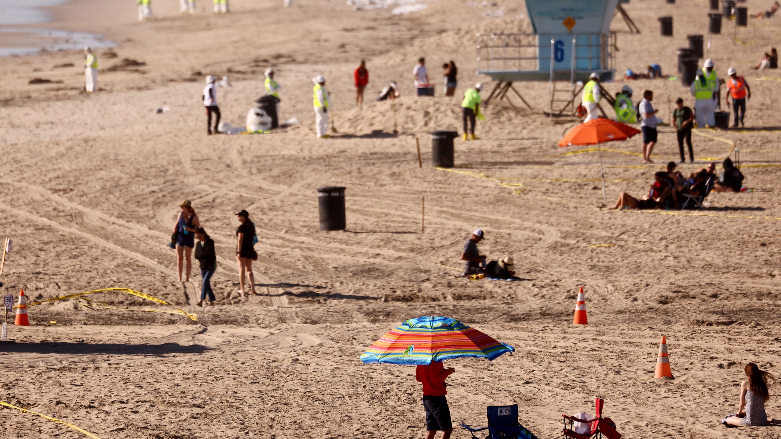 Cleanup workers search for contaminated sand and seaweed on a mostly empty Huntington Beach about one week after an oil spill from an offshore oil platform on Oct. 9, 2021. (Mario Tama / Getty Images)