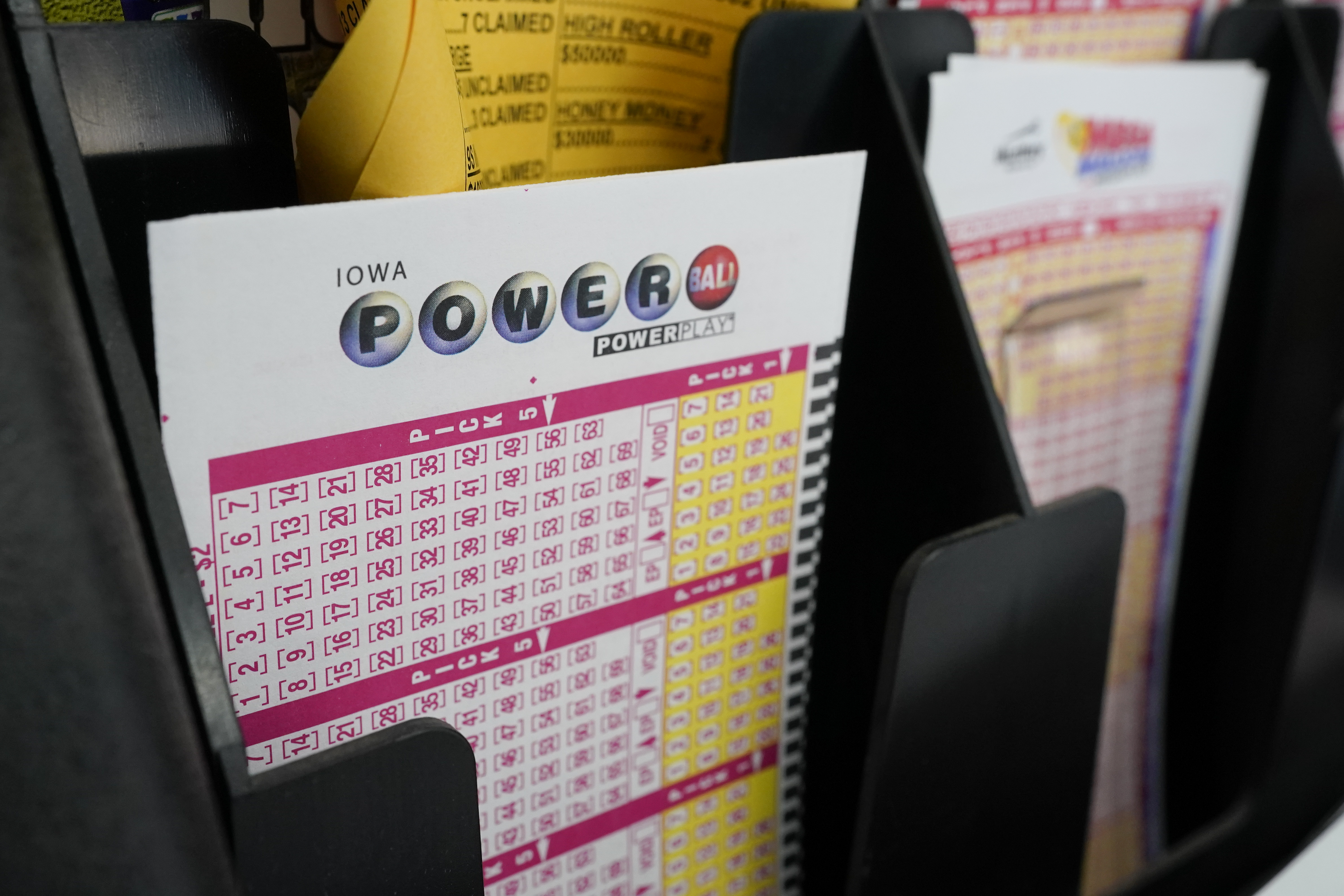 In this Jan. 12, 2021 file photo, blank forms for the Powerball lottery sit in a bin at a local grocery store, in Des Moines, Iowa. The giant Powerball jackpot has grown even bigger, with officials raising the estimated payout ahead of Saturday, Oct. 2, drawing.(AP Photo/Charlie Neibergall)