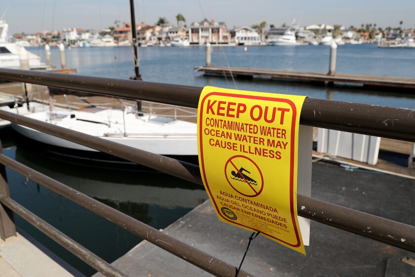 A sign warns pedestrians not to swim in the contaminated water at Huntington Harbour on Oct. 20, 2021, in Huntington Beach. (Kevin Chang / L.A. Times Community News)