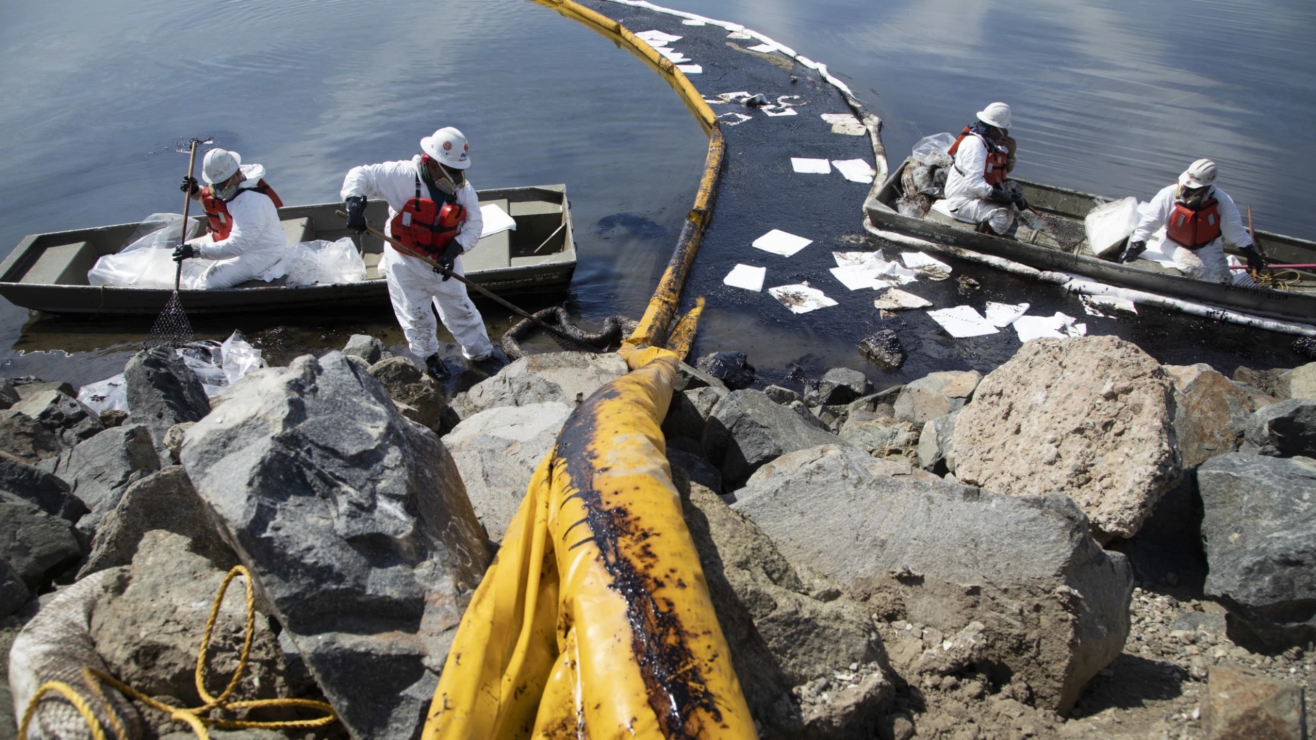 Workers with Patriot Environmental Services place containment booms to trap oil that flowed from an offshore pipeline leak into the Talbert Marsh in Huntington Beach on Sunday.(Myung J. Chun/Los Angeles Times)