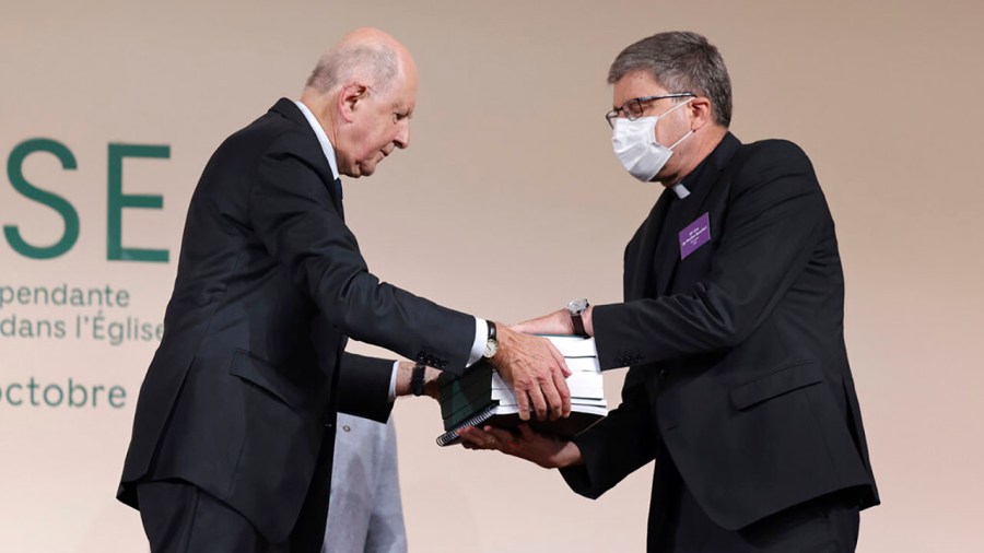 Commission president Jean-Marc Sauve, left, hands copies of the report to Catholic Bishop Eric de Moulins-Beaufort, president of the Bishops' Conference of France (CEF), during the publishing of a report by an independant commission into sexual abuse by church officials (Ciase), Tuesday, Oct. 5, 2021, in Paris. A major French report released Tuesday found that an estimated 330,000 children were victims of sex abuse within France's Catholic Church over the past 70 years, in France's first major reckoning with the devastating phenomenon. (Thomas Coex, Pool via AP)