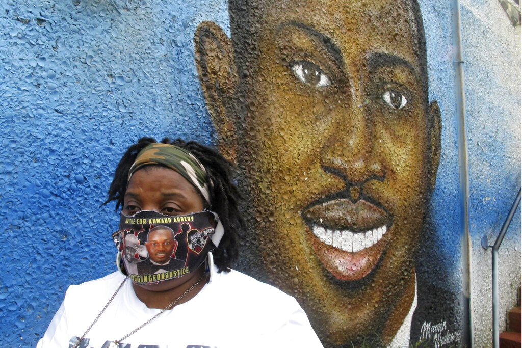 Thea Brooks stands in front of a mural of her slain nephew, Ahmaud Arbery, in Brunswick Ga., Oct. 5, 2021. (AP Photo/Russ Bynum)