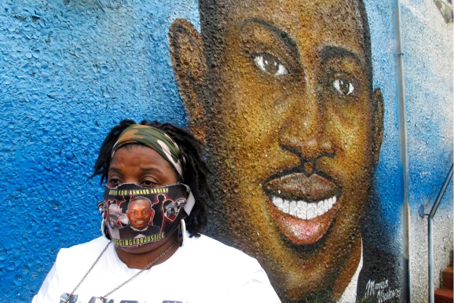 Thea Brooks stands in front of a mural of her slain nephew, Ahmaud Arbery, in Brunswick Ga., Oct. 5, 2021. (AP Photo/Russ Bynum)