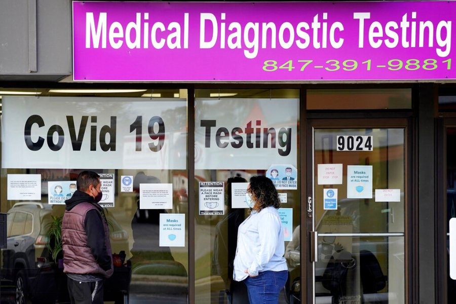 In this Oct. 21, 2020, file photo, an Exam Corp Lab employee, right, wears a mask as she talks with a patient lined up for COVID-19 testing in Niles, Ill. (AP Photo/Nam Y. Huh, File)