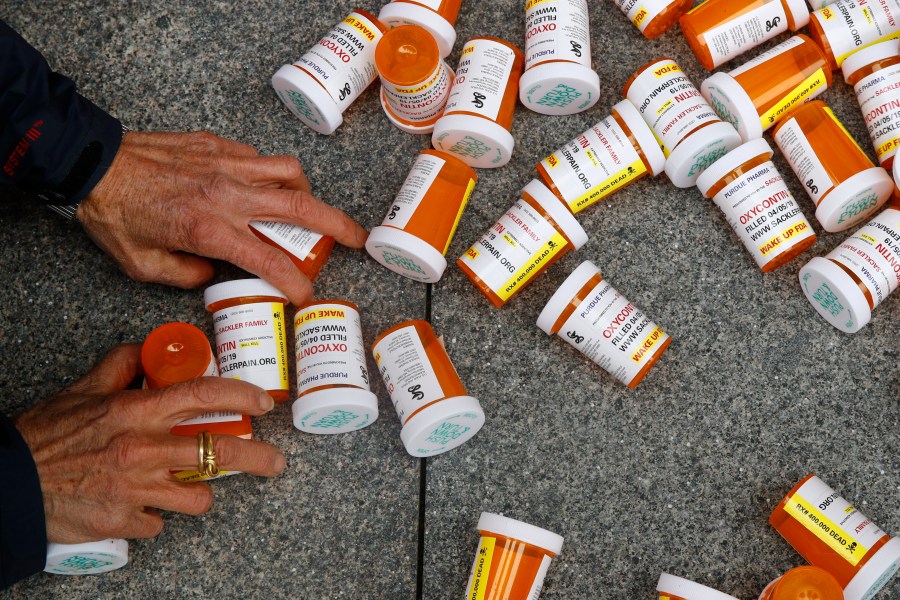 A protester gathers containers that look like OxyContin bottles at an anti-opioid demonstration in front of the U.S. Department of Health and Human Services headquarters in Washington on April 5, 2019. A California judge has ruled for top drug manufacturers as local governments seek billions of dollars to cover their costs from the nation’s opioid epidemic. Orange County Superior Court Judge Peter Wilson issued a tentative ruling Monday, Nov. 1, 2021, that said the governments hadn't proven the pharmaceutical companies used deceptive marketing to increase unnecessary opioid prescriptions and create a public nuisance. (AP Photo/Patrick Semansky, File)