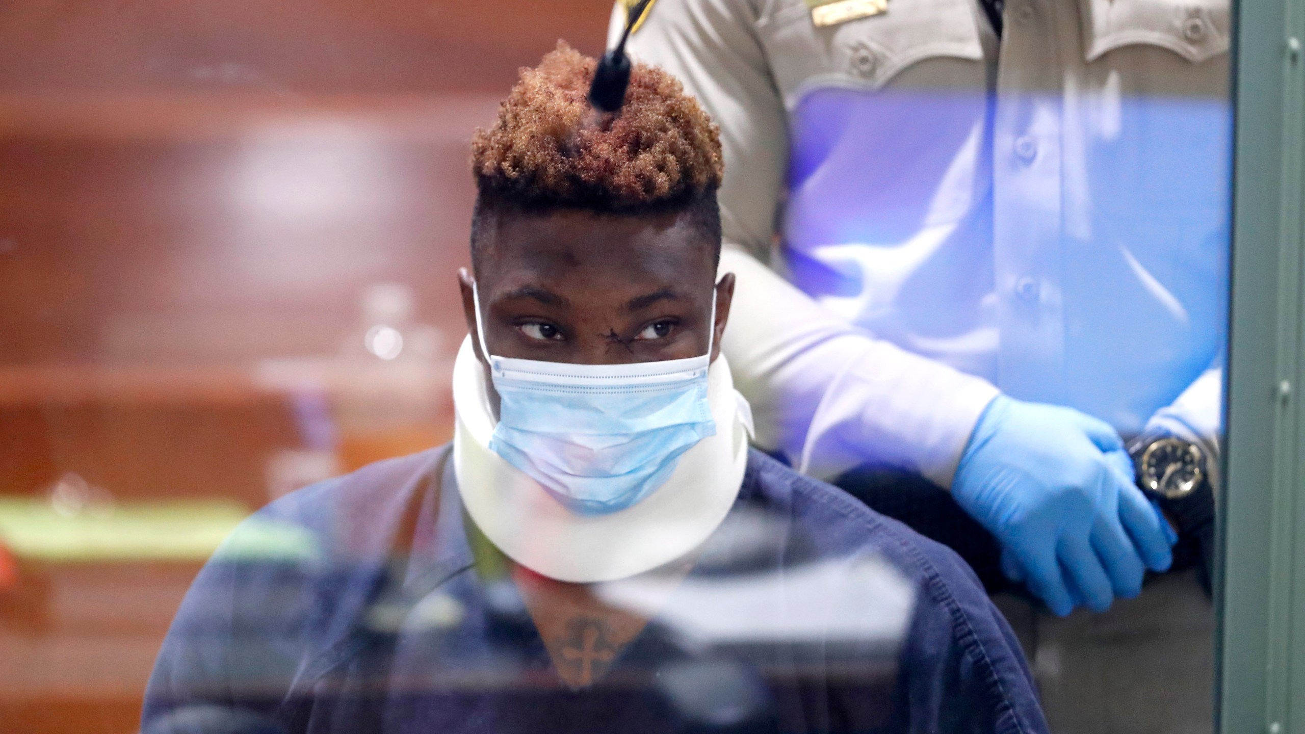 Former Las Vegas Raiders wide receiver Henry Ruggs III makes an initial appearance in Las Vegas Justice Court in Las Vegas, Wednesday, Nov. 3, 2021. Ruggs is facing charges relating to a fiery vehicle crash early Tuesday in Las Vegas that left a woman dead and Ruggs and his female passenger injured. Photo is taken through a glass window. The team released Ruggs just hours after the crash. (Steve Marcus/Las Vegas Sun via AP)