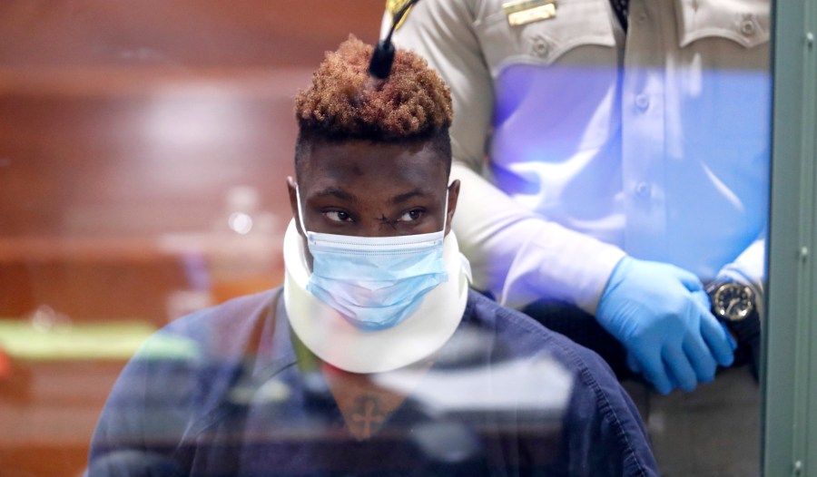 Former Las Vegas Raiders wide receiver Henry Ruggs III makes an initial appearance in Las Vegas Justice Court in Las Vegas, Wednesday, Nov. 3, 2021. Ruggs is facing charges relating to a fiery vehicle crash early Tuesday in Las Vegas that left a woman dead and Ruggs and his female passenger injured. Photo is taken through a glass window. The team released Ruggs just hours after the crash. (Steve Marcus/Las Vegas Sun via AP)