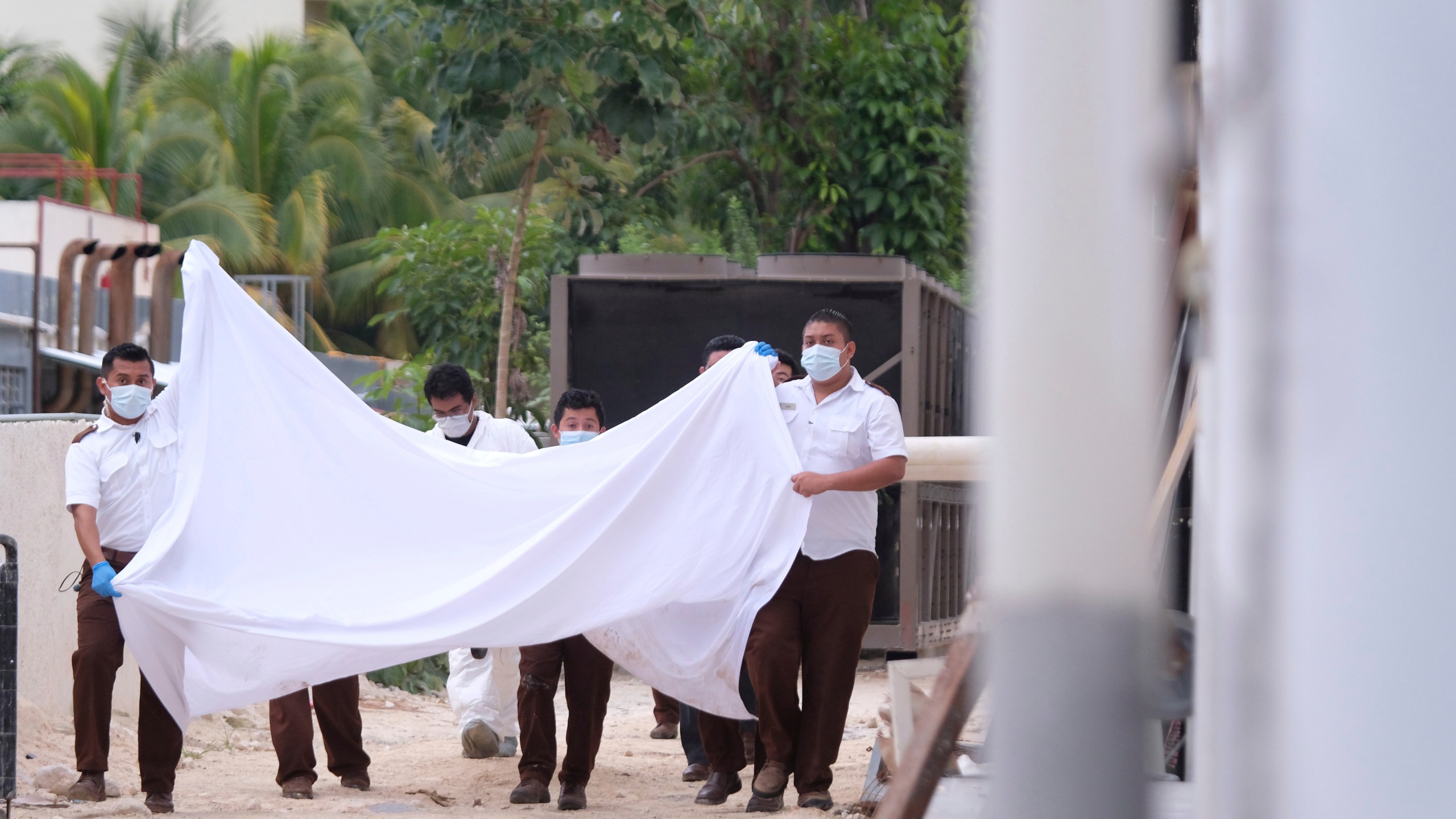 Police hold a bed sheet in an attempt to block onlookers after an armed confrontation close to a hotel near Puerto Morelos, Mexico, Thursday, November 4, 2021. Two suspected drug dealers were killed after gunmen from competing gangs staged a dramatic shootout near upscale hotels that sent foreign tourists scrambling for cover. (AP Photo/Karim Torres)