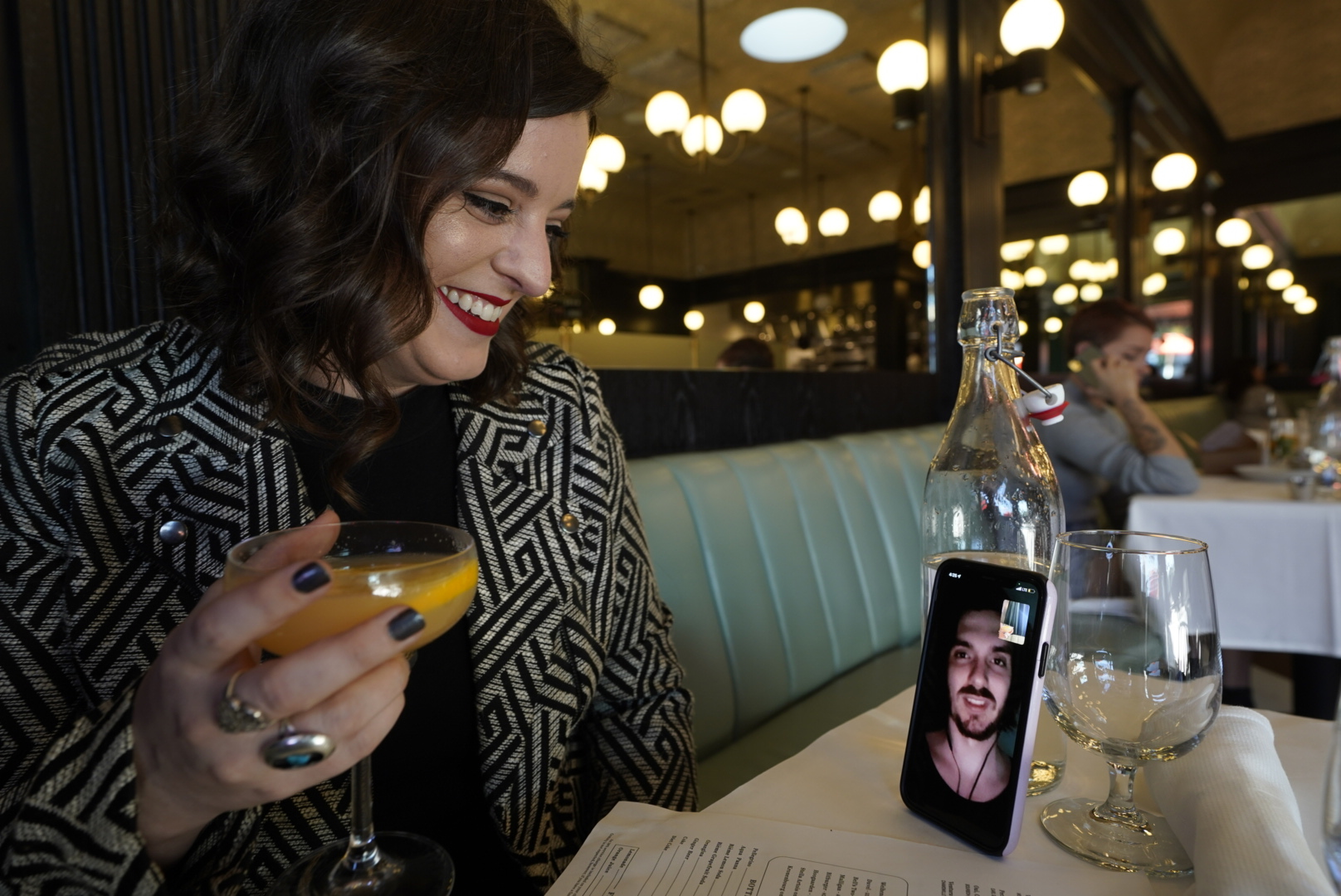 Erin Tridle holds a video chat with her boyfriend Jordan Commarrieu living in Paris from their favorite French restaurant "Petit Trois" in Los Angeles on Friday, Nov. 5, 2021. (AP Photo/Damian Dovarganes)