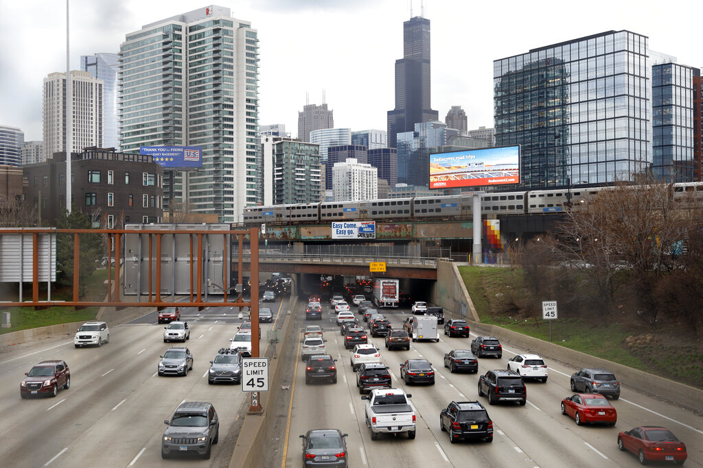 In this March 31, 2021,photo, traffic flows along Interstate 90 highway as a Metra suburban commuter train moves along an elevated track in Chicago. (AP Photo/Shafkat Anowar, File)