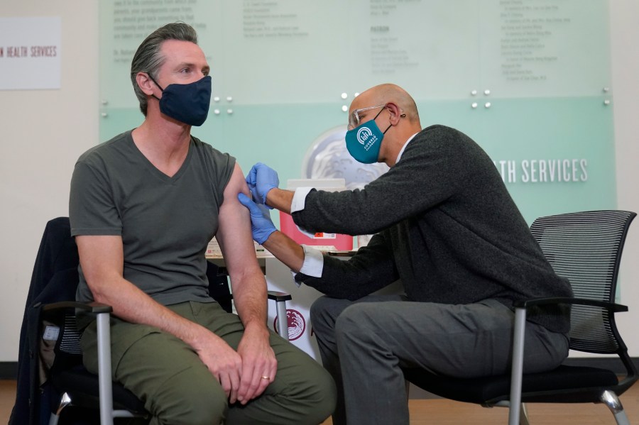 Gov. Gavin Newsom, left, receives a Moderna COVID-19 vaccine booster shot from California Health and Human Services Secretary Dr. Mark Ghaly at Asian Health Services in Oakland on Oct. 27, 2021. (AP Photo/Jeff Chiu, File)