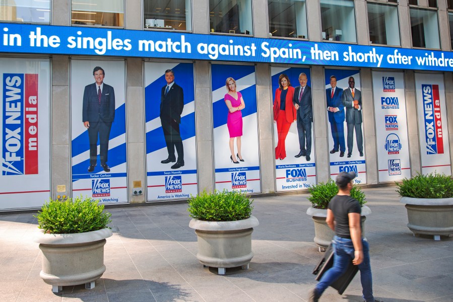 A man walks past promotional posters outside Fox News studios at News Corporation headquarters in New York on Saturday, July 31, 2021. From left to right are hosts Tucker Carlson, Sean Hannity, Laura Ingraham, Maria Bartiromo, Stuart Varney, Neil Cavuto and Charles Payne. (AP Photo/Ted Shaffrey, File)