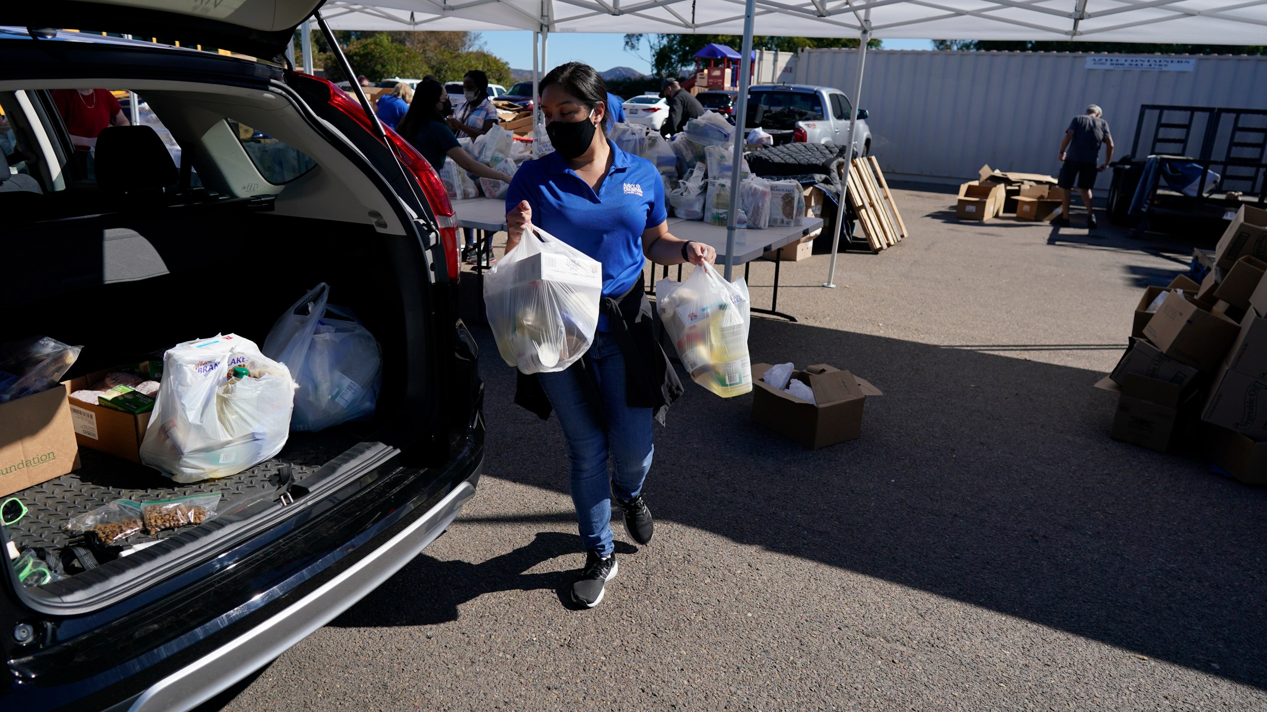 A volunteer loads food into a car at an Armed Services YMCA food distribution, Oct. 28, 2021, in San Diego. As many of 160,000 active duty military members are having trouble feeding their families, according to Feeding America, which coordinates the work of more than 200 food banks around the country. (AP Photo/Gregory Bull)