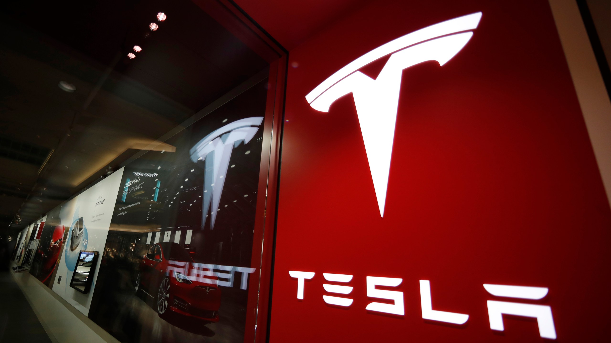 This Feb. 9, 2019, file photo shows a sign bearing the company logo outside a Tesla store in Cherry Creek Mall in Denver. (AP Photo/David Zalubowski, File)