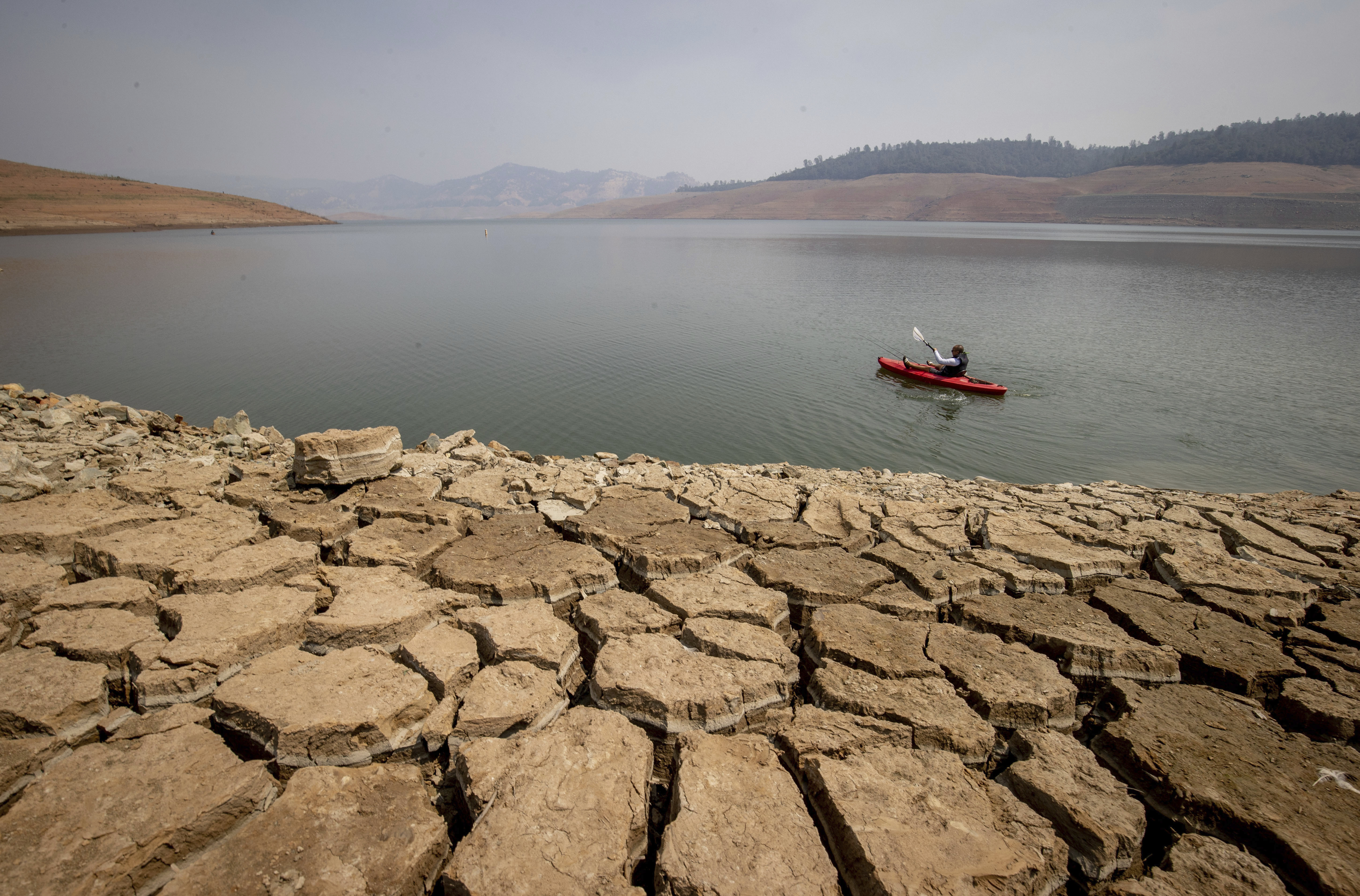 A kayaker fishes in Lake Oroville as water levels remain low due to continuing drought conditions in Oroville, Calif., on Aug. 22, 2021. (AP Photo/Ethan Swope, File)