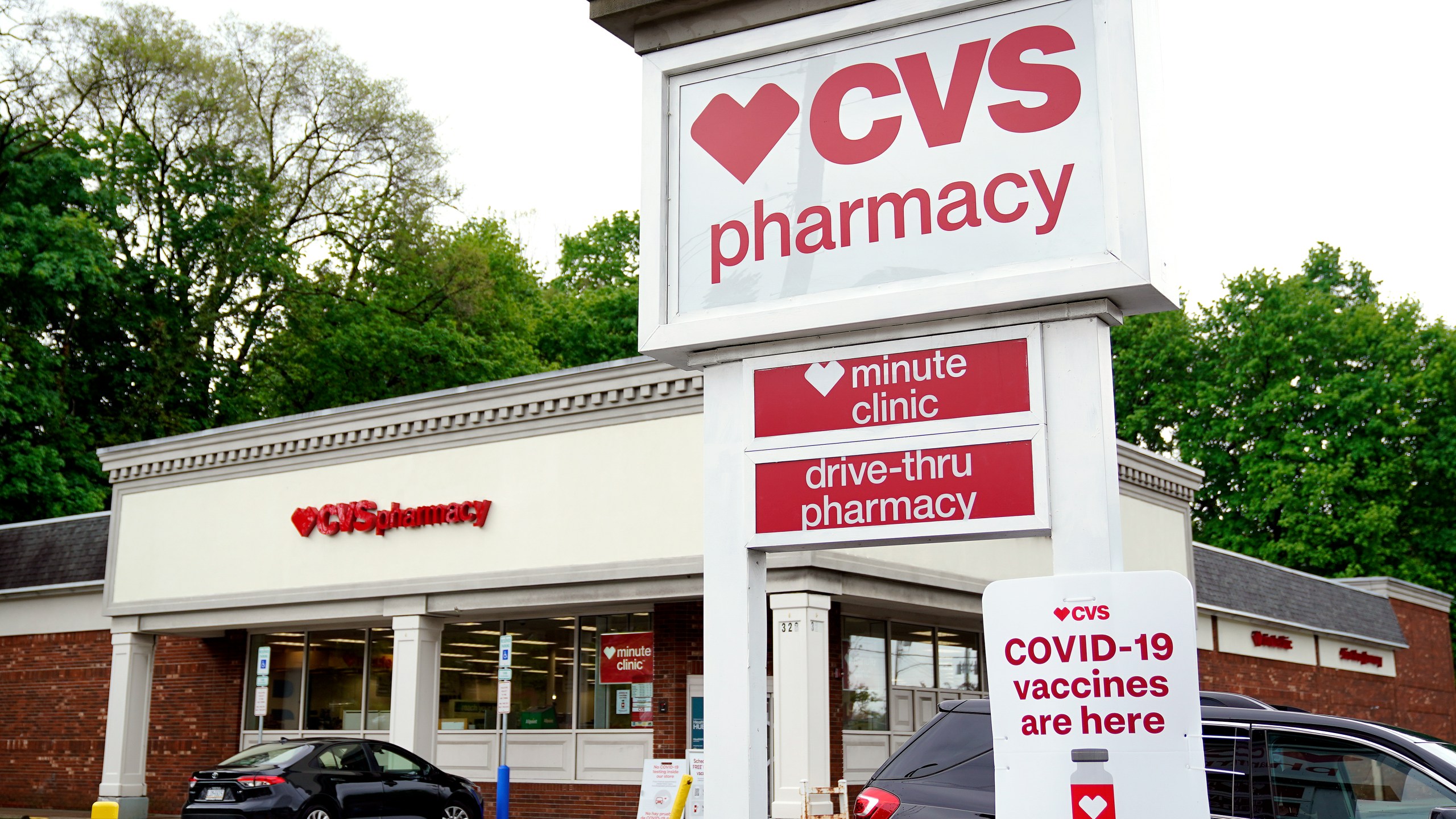 Vehicles are parked in front of a CVS Pharmacy in Mount Lebanon, Pa., on Monday May 3, 2021. CVS Health will close hundreds of drugstores over the next three years, as the retail giant adjusts to changing customer needs and converts to new store formats. The company said Thursday, Nov. 18, that it will close about 300 stores a year for the next three years as it looks to reduce store count density in some locations. (AP Photo/Gene J. Puskar)