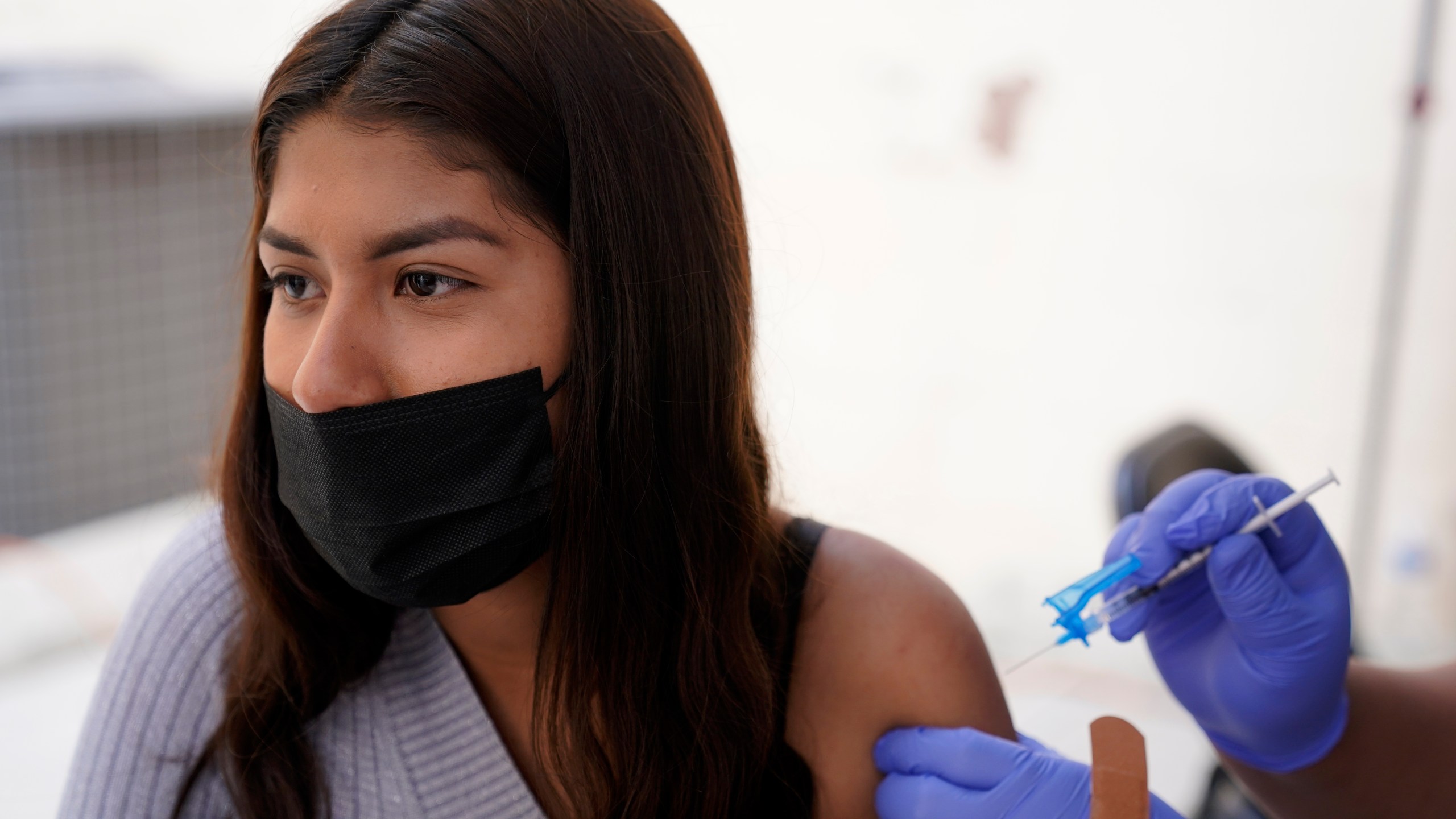 A young woman from Tijuana, Mexico, receives a vaccination shot against the coronavirus outside of the Mexican Consulate building on Nov. 18, 2021, in San Diego. Scores of Mexican adolescents were bused to California to get vaccinated against the coronavirus as efforts get underway across Mexico to get shots in the arms of teens. (AP Photo/Gregory Bull)