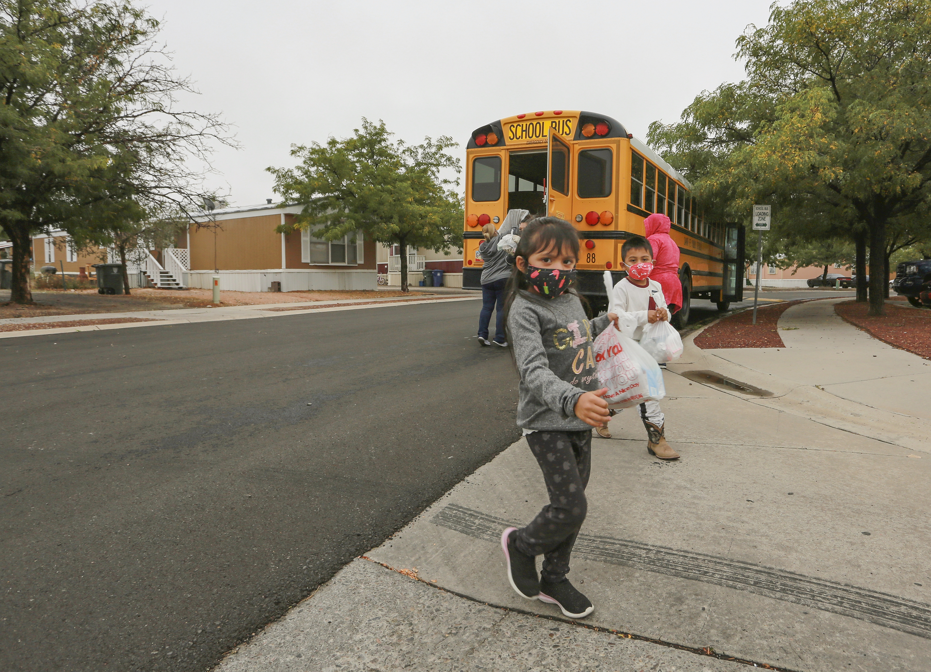 Kindergarteners who are learning remotely during the coronavirus pandemic pick up meals at a bus stop near their home in Santa Fe, N.M., on Sept. 9, 2020. The Santa Fe school district decided last week to close its doors on Nov. 23, 2021, and pivot to remote learning in a bid to reduce virus outbreaks ahead of the Thanksgiving holiday. (Cedar Attanasio/Associated Press)