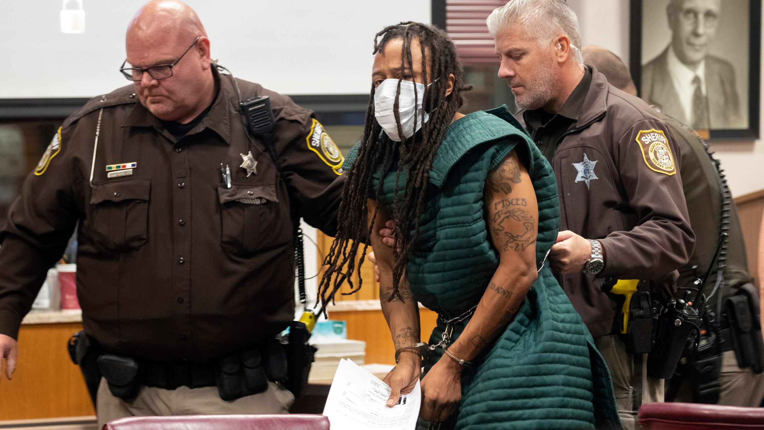 Darrell Brooks, center, is escorted out of the courtroom after making his initial appearance on Nov. 23, 2021, in Waukesha County Court in Waukesha, Wis. Prosecutors in Wisconsin have charged Brooks with intentional homicide in the deaths of at least five people who were killed when an SUV was driven into a Christmas parade. (Mark Hoffman/Milwaukee Journal-Sentinel via AP, Pool)