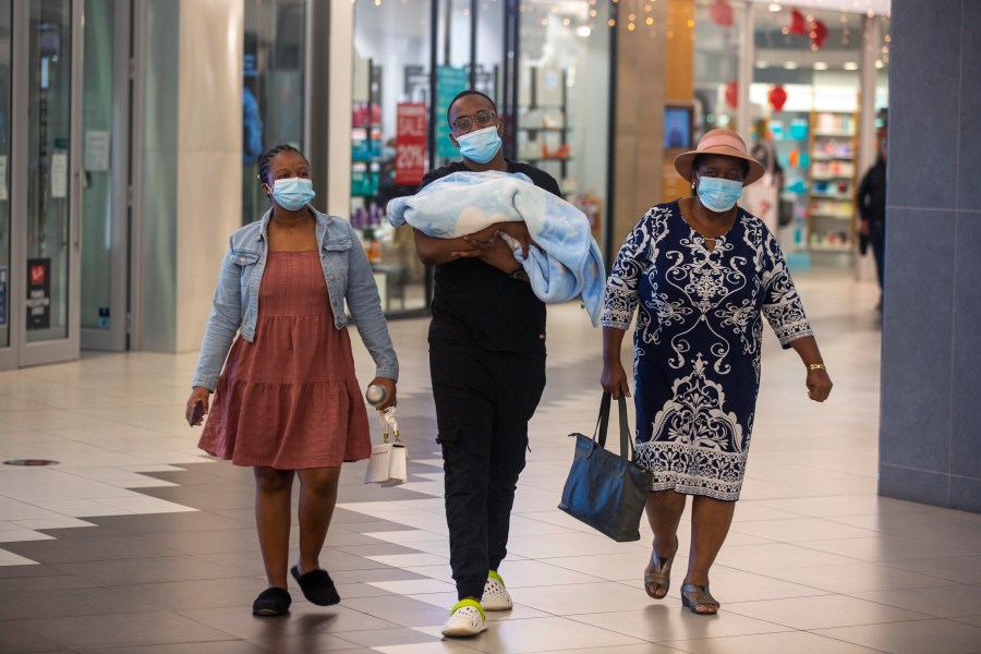 People with masks walk at a shopping mall in Johannesburg, South Africa on Nov. 26, 2021. (AP Photo/Denis Farrell)