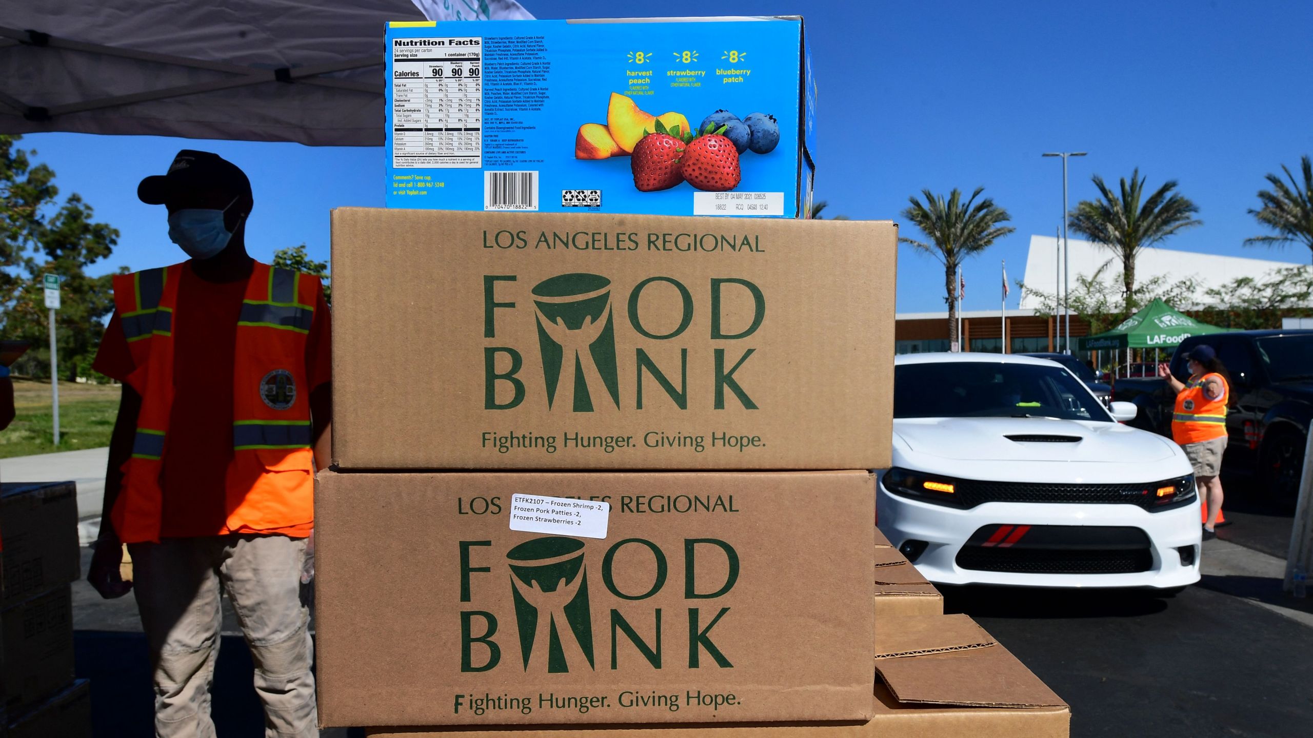 Los Angeles County Regional Food Bank workers help with food distribution to some 2,000 vehicles in Willowbrook, California on April 29, 2021 in an ongoing effort to help people affected by the coronavirus pandemic. (FREDERIC J. BROWN/AFP via Getty Images)