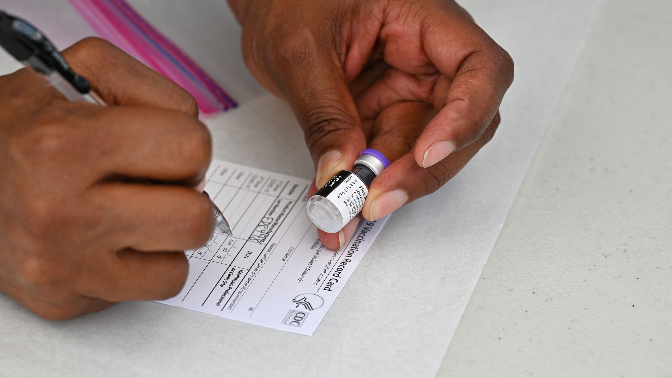 A healthcare worker fills out a Covid-19 vaccination card at a community healthcare event in a predominately Latino neighborhood in Los Angeles, Aug. 11, 2021. (ROBYN BECK/AFP via Getty Images)