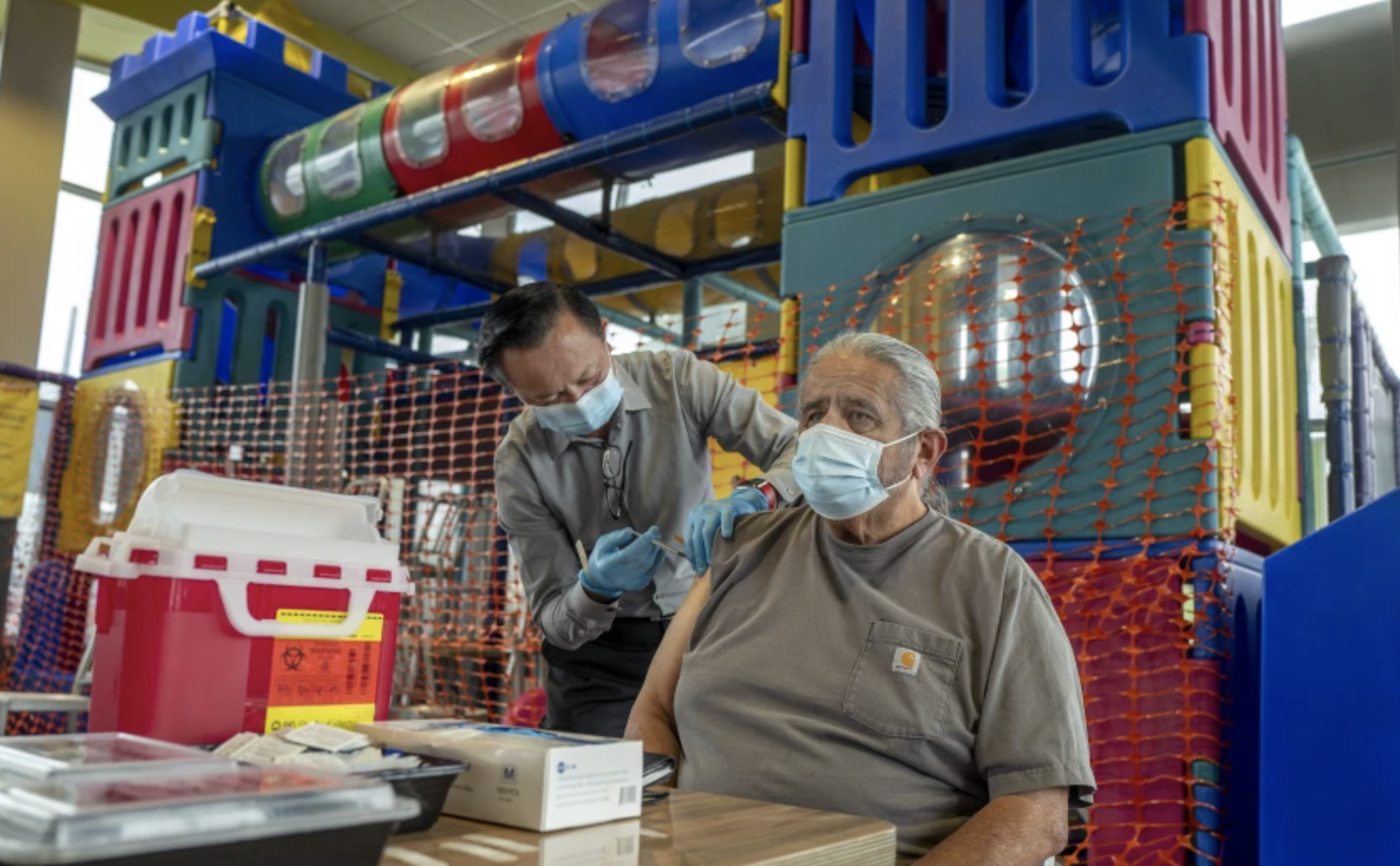 Pharmacist Ryan Le gives Jim Canales, 78, of Fullerton a booster shot of Pfizer-BioNTech vaccine at a McDonald’s in September. (Francine Orr / Los Angeles Times)