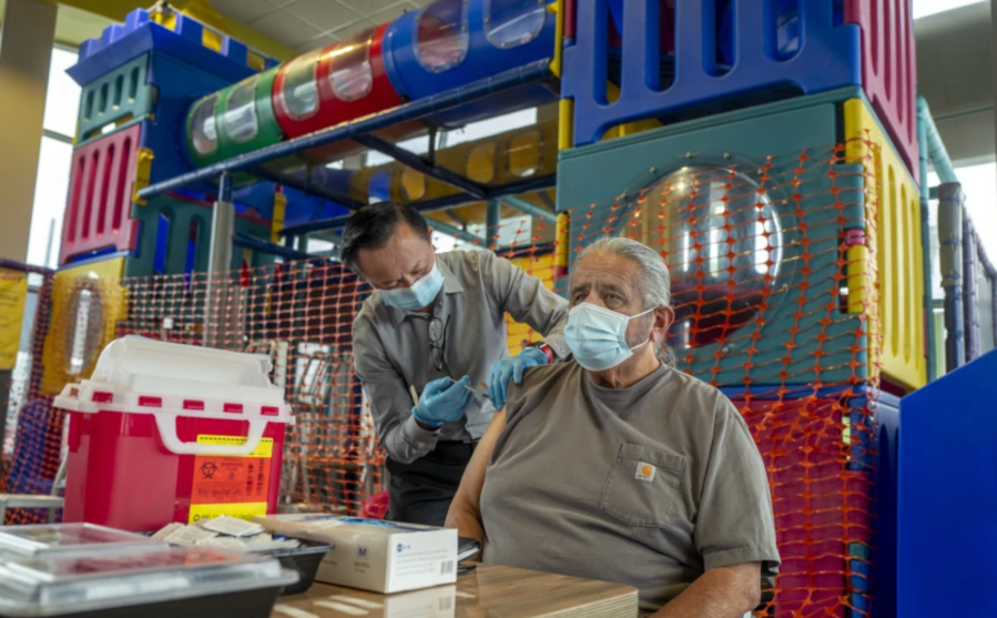 Pharmacist Ryan Le gives Jim Canales, 78, of Fullerton a booster shot of Pfizer-BioNTech vaccine at a McDonald’s in September. (Francine Orr / Los Angeles Times)