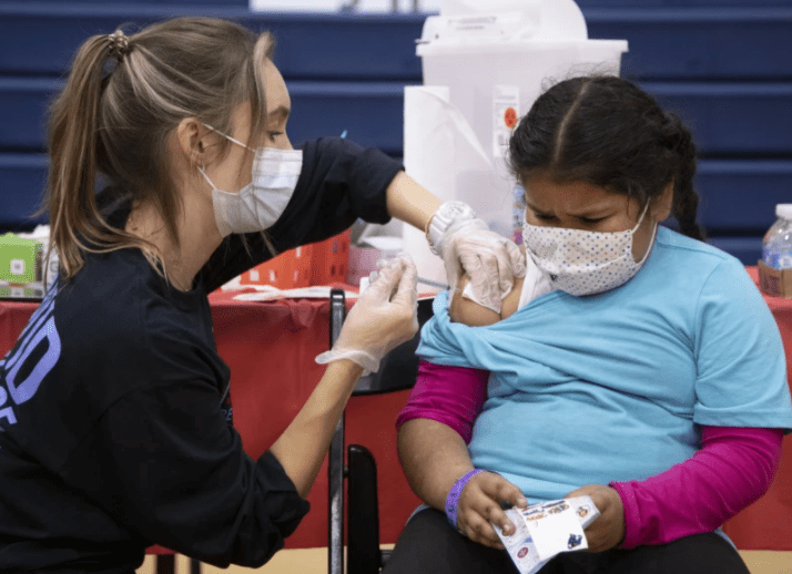 Sarginoor Kaur, 7, gets the COVID-19 vaccine from nurse Chelsea Meyer at Arleta High School on Nov. 8. Children in L.A. Unified schools who are 12 and older must be vaccinated by Jan. 10. Nearly 80% met Sunday’s first-dose deadline.(Myung J. Chun/Los Angeles Times)