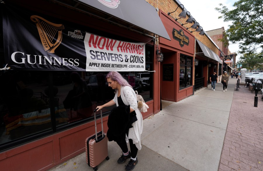 A traveller wheels her baggage past a now hiring sign outside a bar and restaurant Saturday, Oct. 9, 2021, in Sioux Falls, S.D. America’s employers slowed the pace of their hiring in November, adding 210,000 jobs, the lowest monthly gain in nearly a year. Friday, Dec. 3 report from the Labor Department also showed that the nation's unemployment rate tumbled from 4.6% to 4.2% evidence that many more people reported that they had a job. (AP Photo/David Zalubowski)