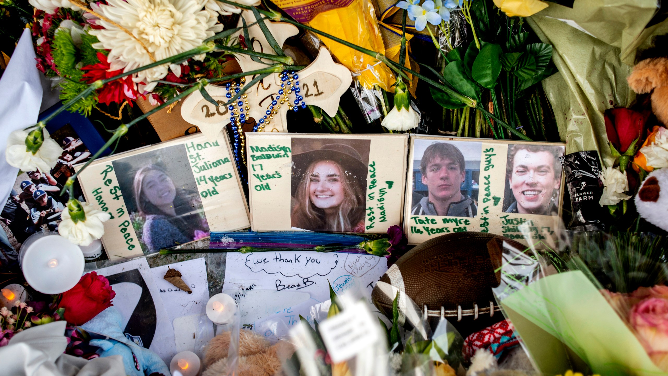 Photographs of four students —Hana St. Juliana, 14, Madisyn Baldwin, 17, Tate Myre, 16 and Justin Shilling, 17 — sit among boquets of flowers, teddy bears and other personal items left at the memorial site on Tuesday, Dec. 7, 2021 outside Oxford High School in Oxford, Mich., after a 15-year-old allegedly killed these four classmates, and injured seven others in a shooting inside the northern Oakland County school one week earlier. (Jake May/The Flint Journal via AP)