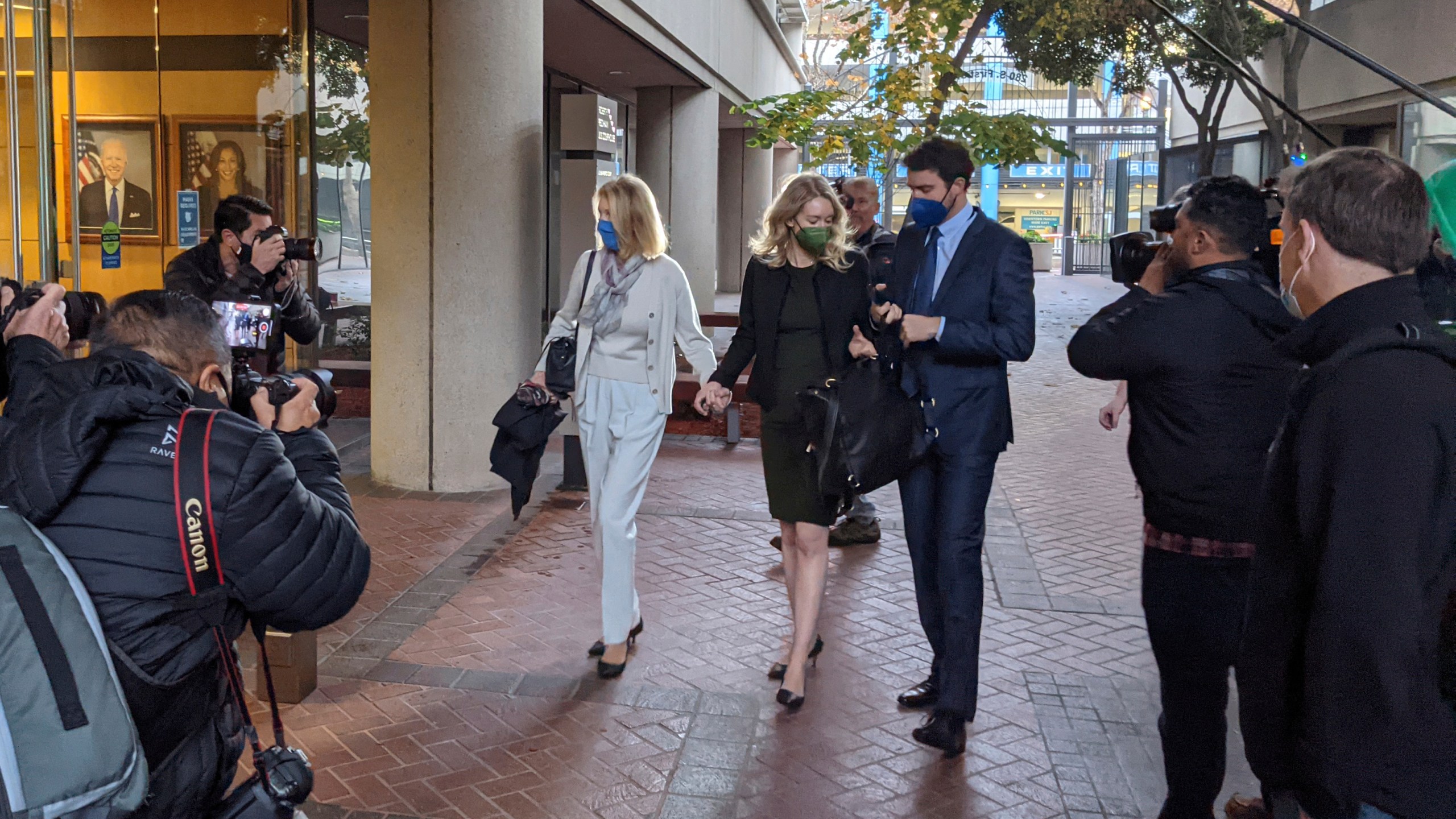 Elizabeth Holmes, center, enters the Robert F. Peckham Federal Building with her partner, Billy Evans, right, and her mother, Noel Holmes, in San Jose, Calif., on Dec. 7, 2021. Looking on at far right is John Carreyrou, the former Wall Street Journal reporter who wrote the October 2015 story that exposed flaws in Theranos' blood-testing technology. (AP Photo/Michael Liedtke)